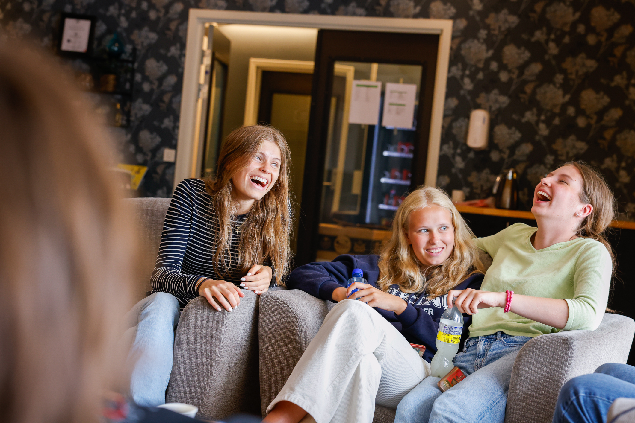 Fire jenter som sitter og ler sammen i en sofa.