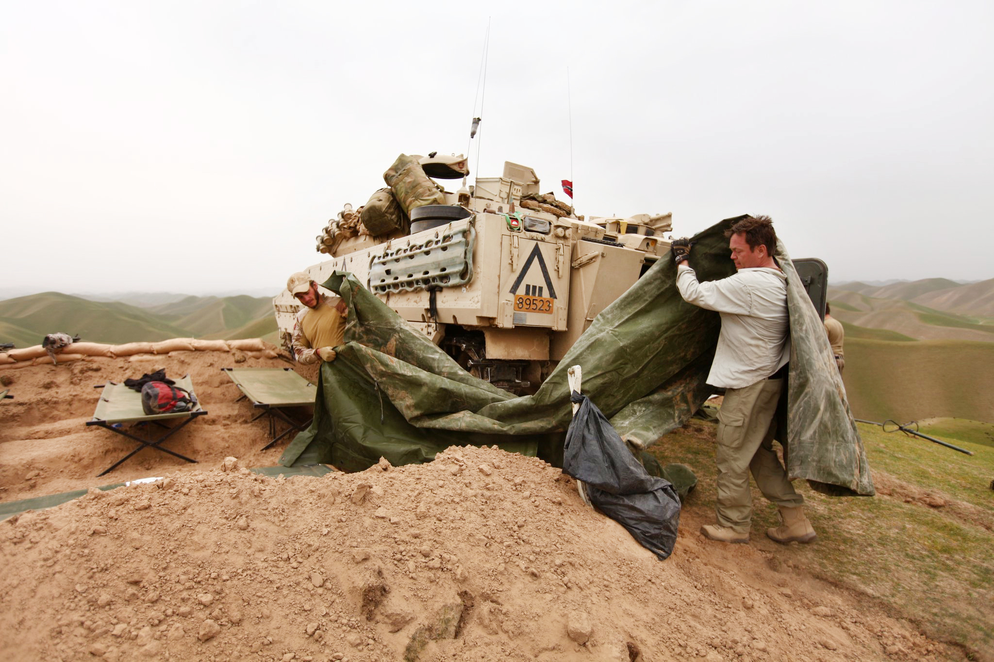Fredrik Græsvik bruker en presenning mot en stridsvogn for å lage husly for natten i Afghanistan