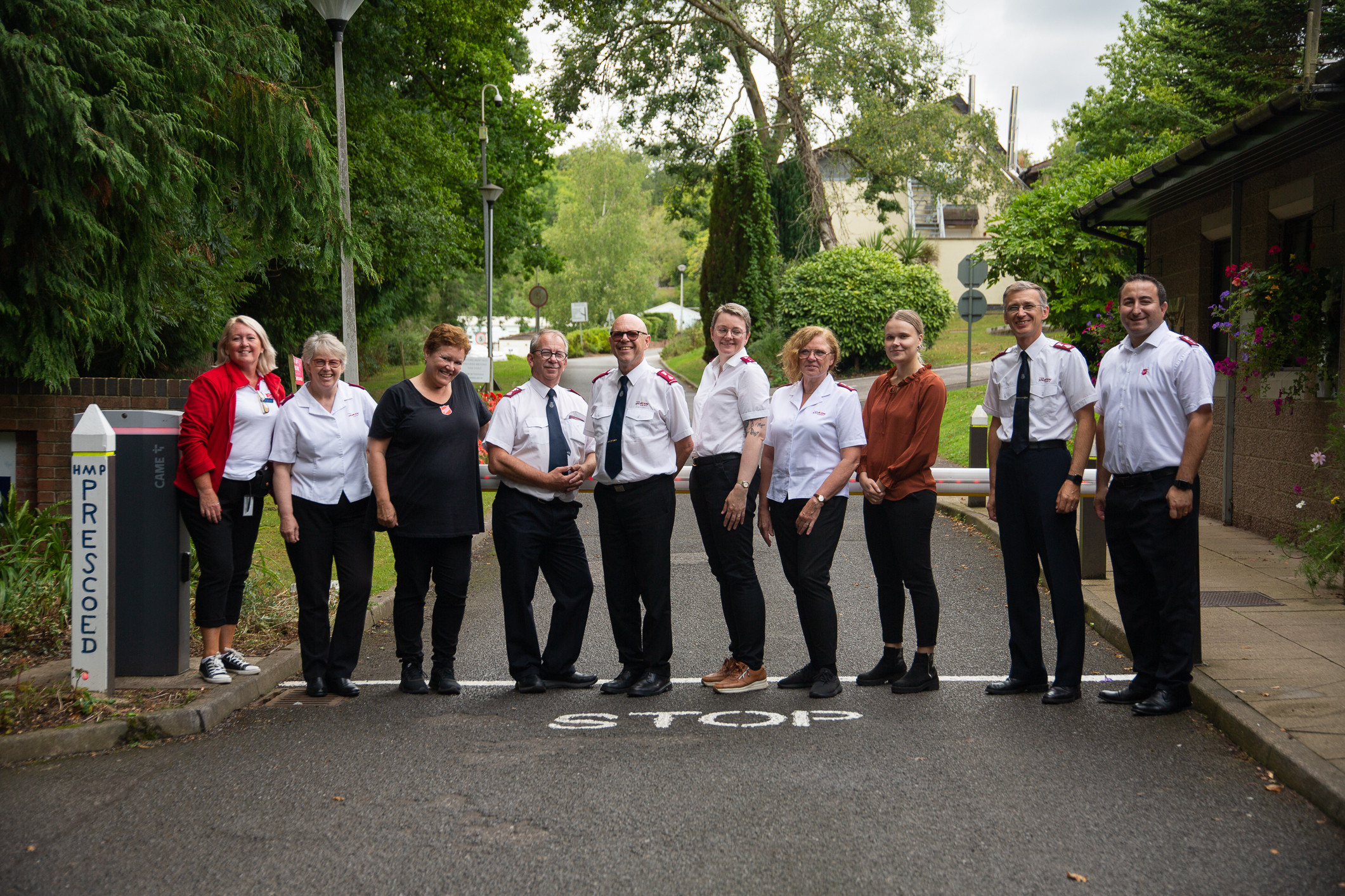 10 ansatte og offiserer fra Frelsesarmeen i Norge står oppstilt ved siden av hverandre i en gate.
