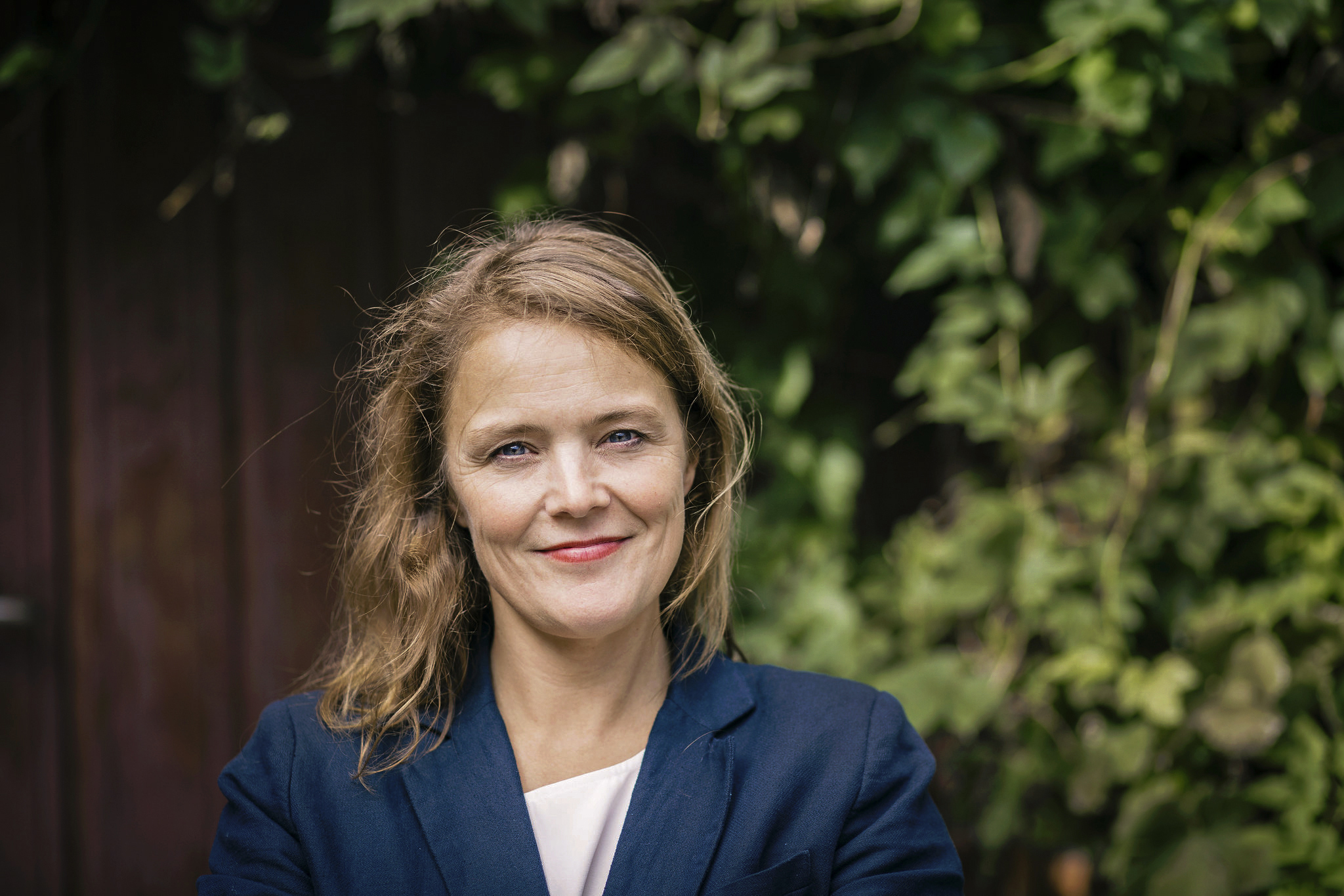 Et portrettbilde av Pernille Huseby. Hun har på seg en blå blazer og smiler til fotografen.