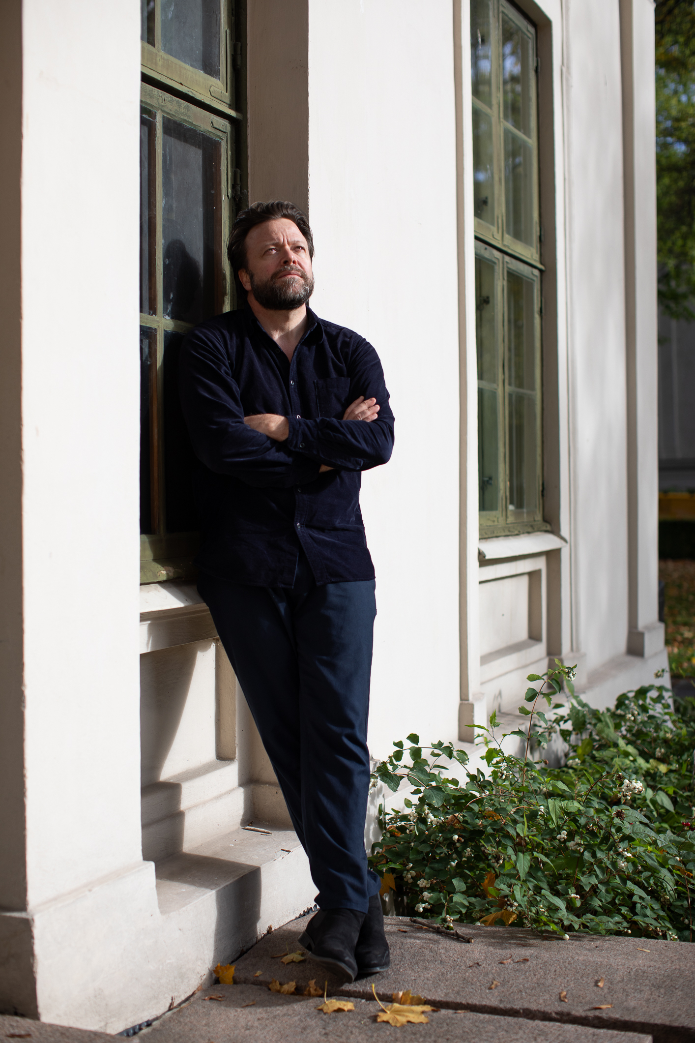 Mann står ut ute og lener seg mot en murvegg. Hode og blikk er rettet oppover.