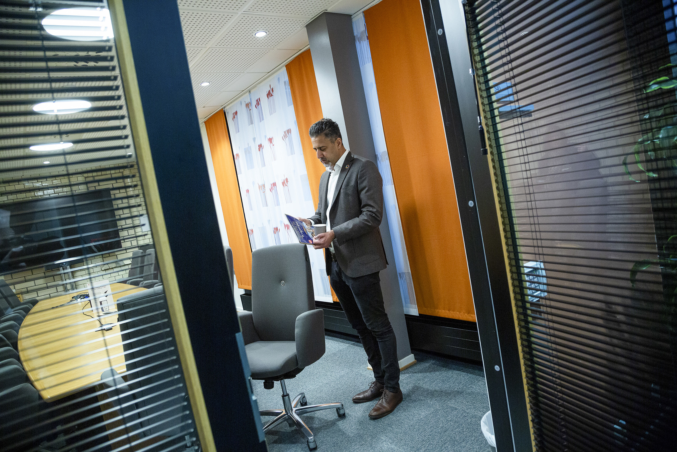 Abid Raja står inne på et kontor og blar i Krigsropets julehefte.