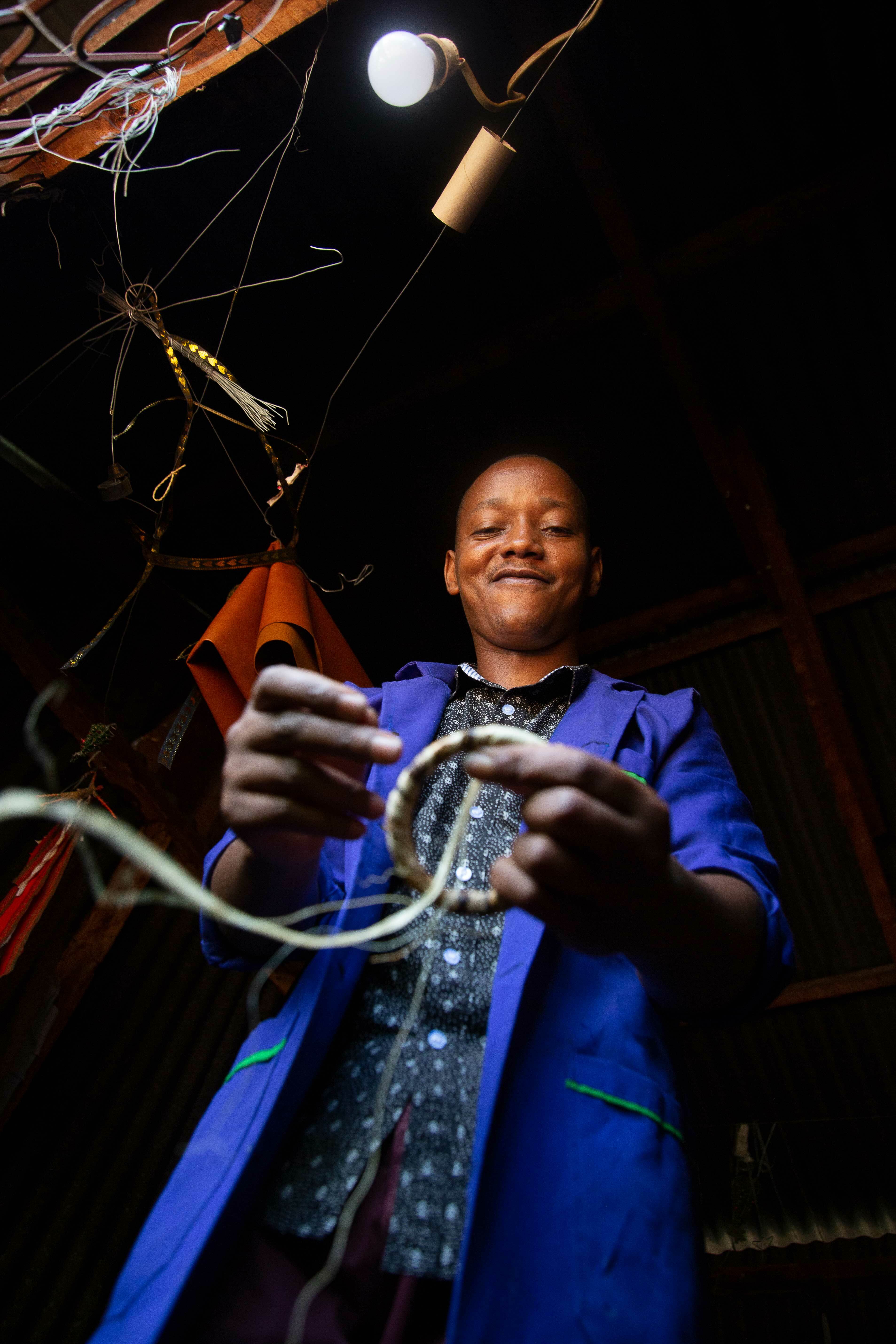 Afrikansk mann smiler når han surrer sial på en ståltråd