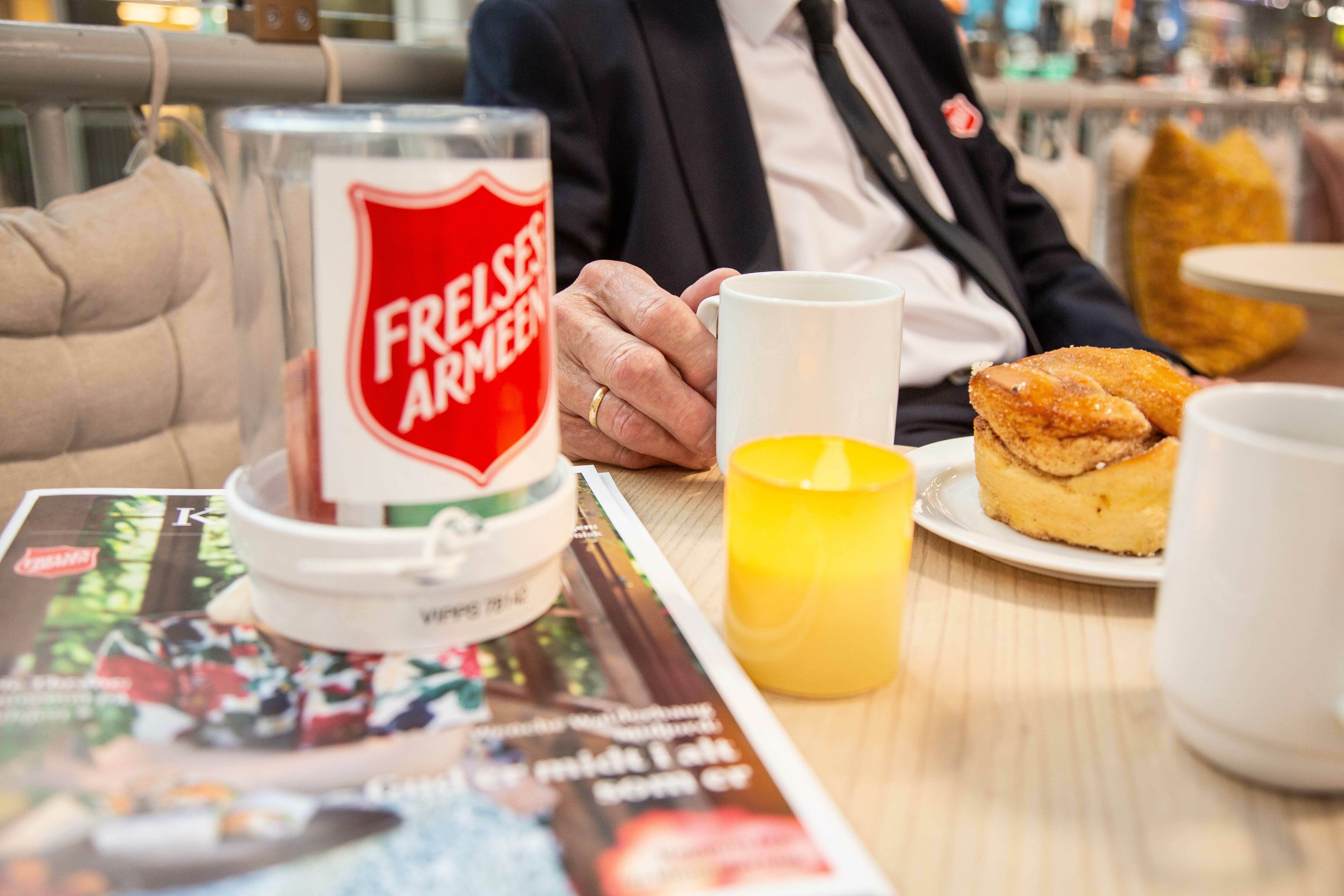 Kaffekopp og en kanelbolle på et kafébord
