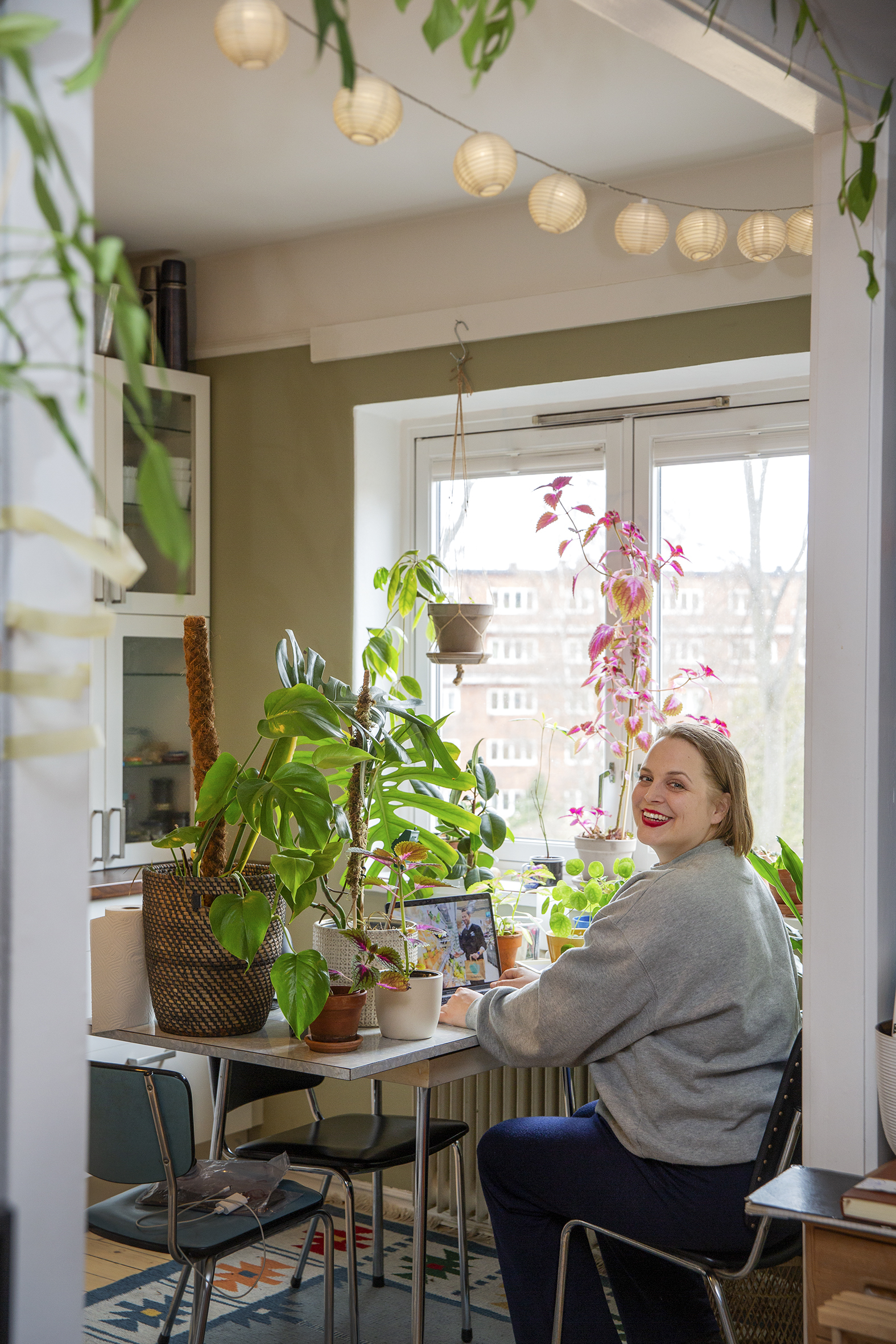 En av Annikens mange planter (bilde t.v.) Anikken sitter ve kjøkkenbordet og demonstrerer på zoom hvordan man potter om planter