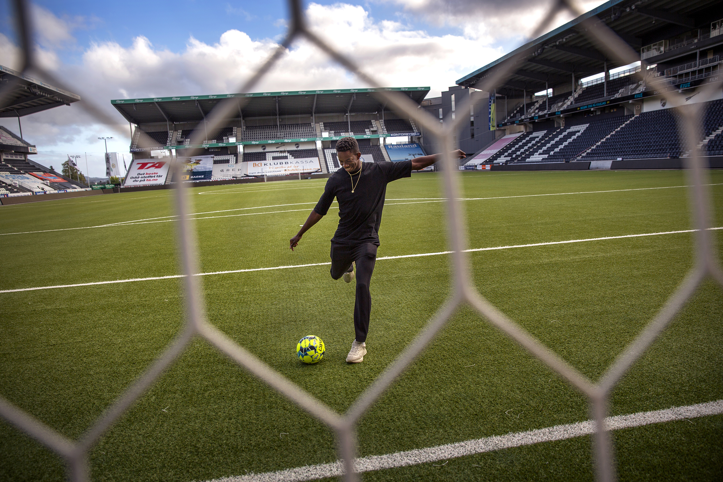 Bildet er tatt gjennom nettet på målet og viser Bakenga som skyter en ball mot mål