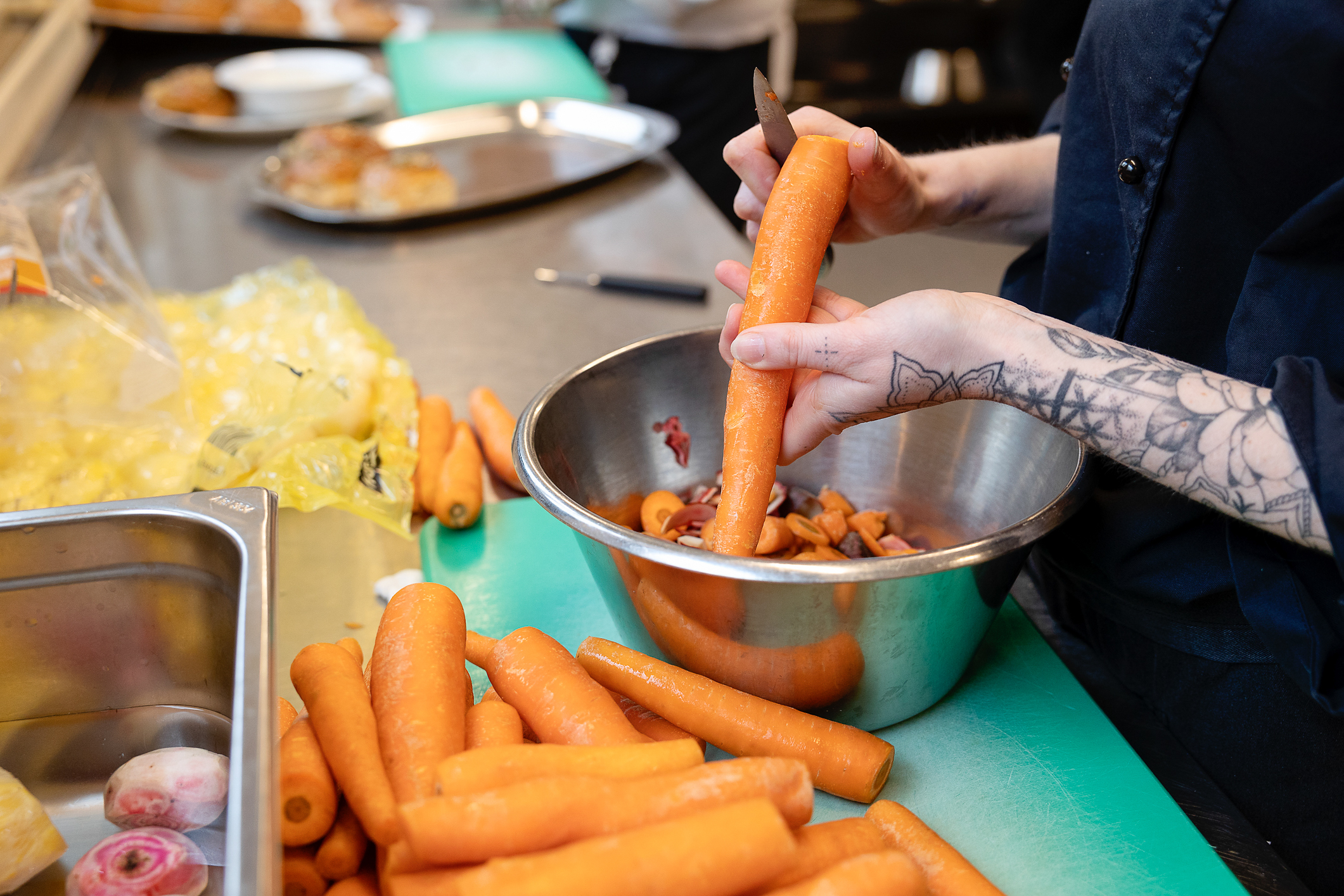 Hender som skreller en hel bunt med gulrøtter.