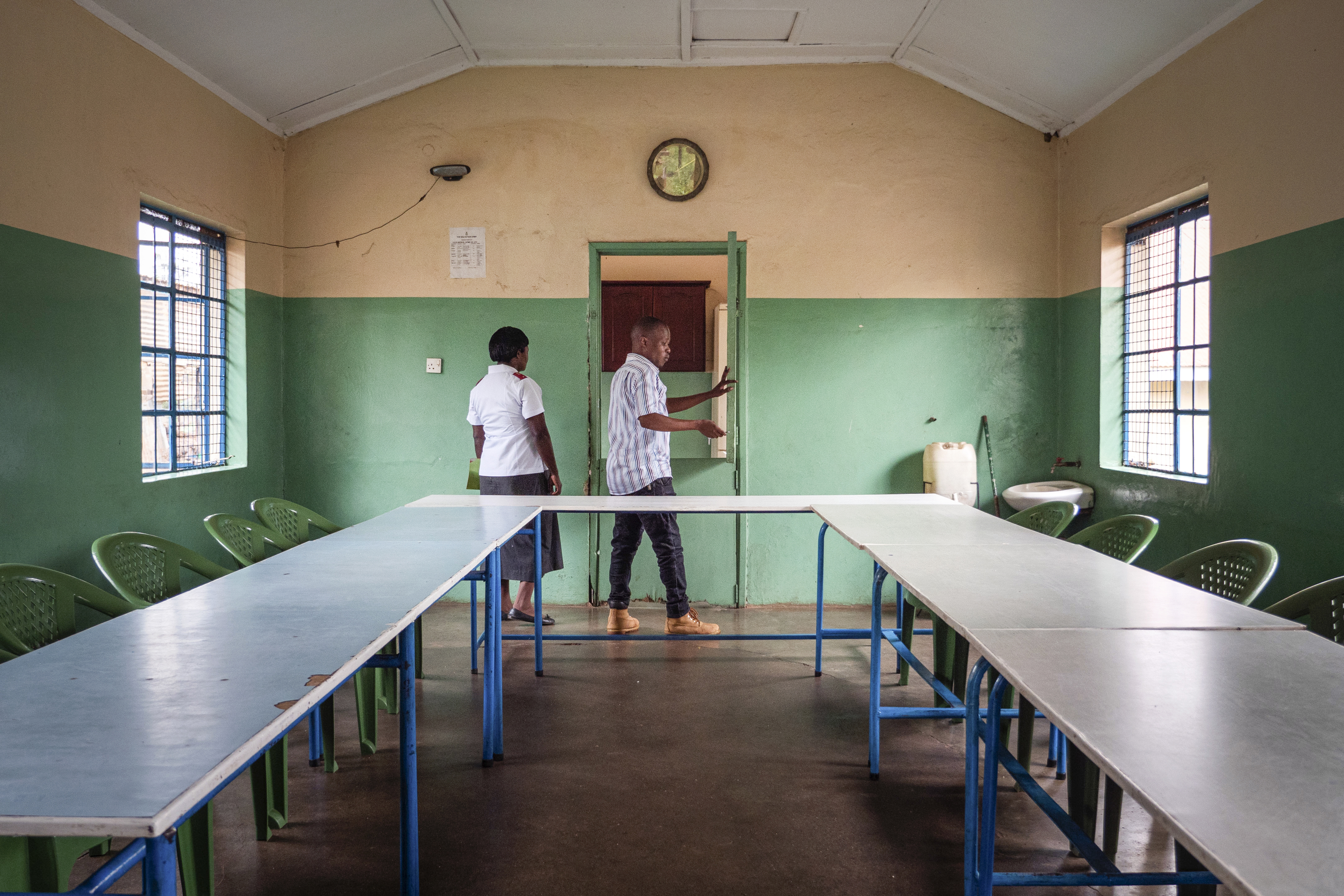 Bildet viser et stort rom med bord satt opp i hesteskoform og stoler rundt. Moses og Gorret sees i bakgrunnen med ryggen mot kamera.
