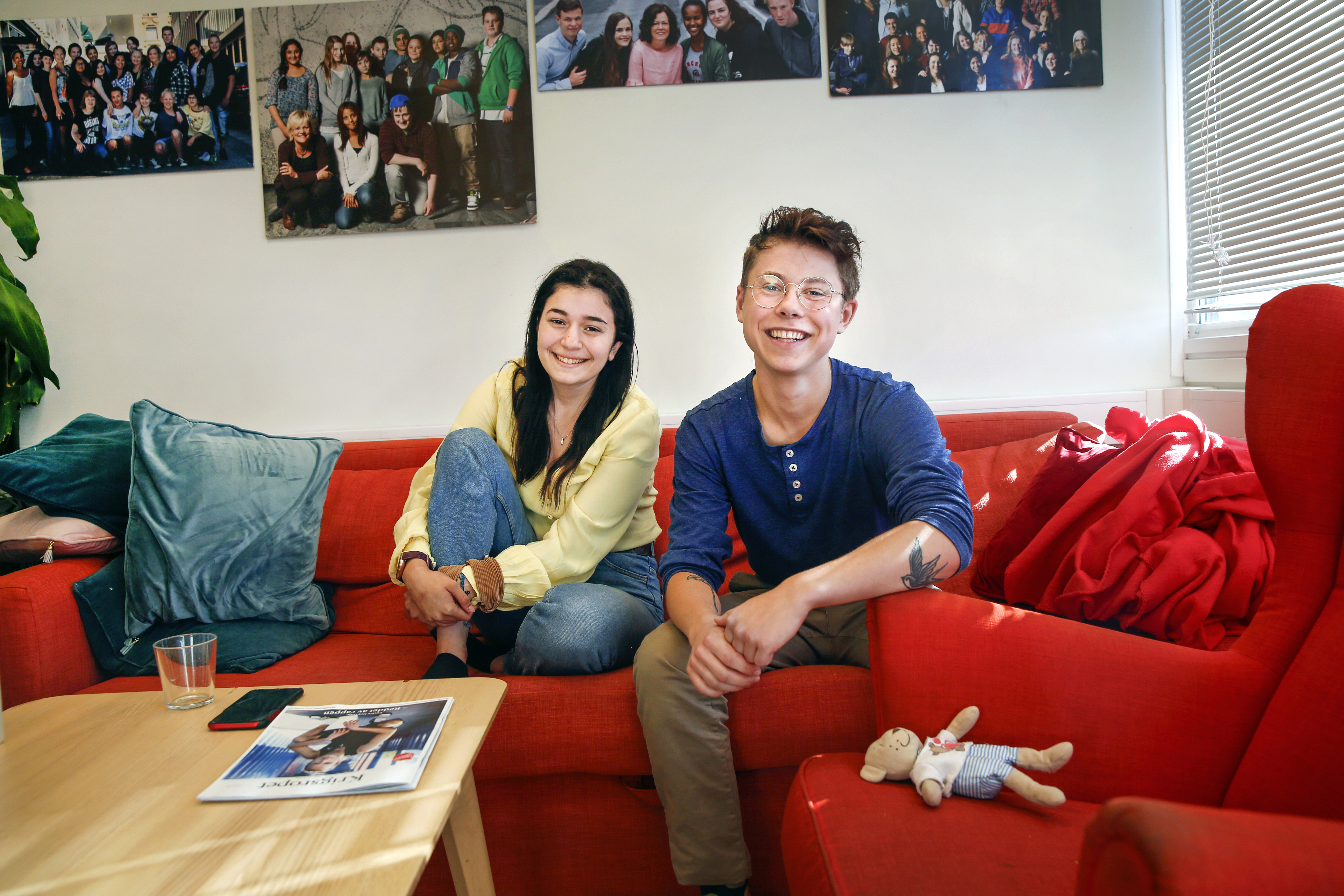 Bildet viser Dania og Leon som sitter i en rød sofa med blå puter i. Dania sitter med bena oppunder seg i sofaen, mens Leon lener seg fram, begge smiler mot kamera