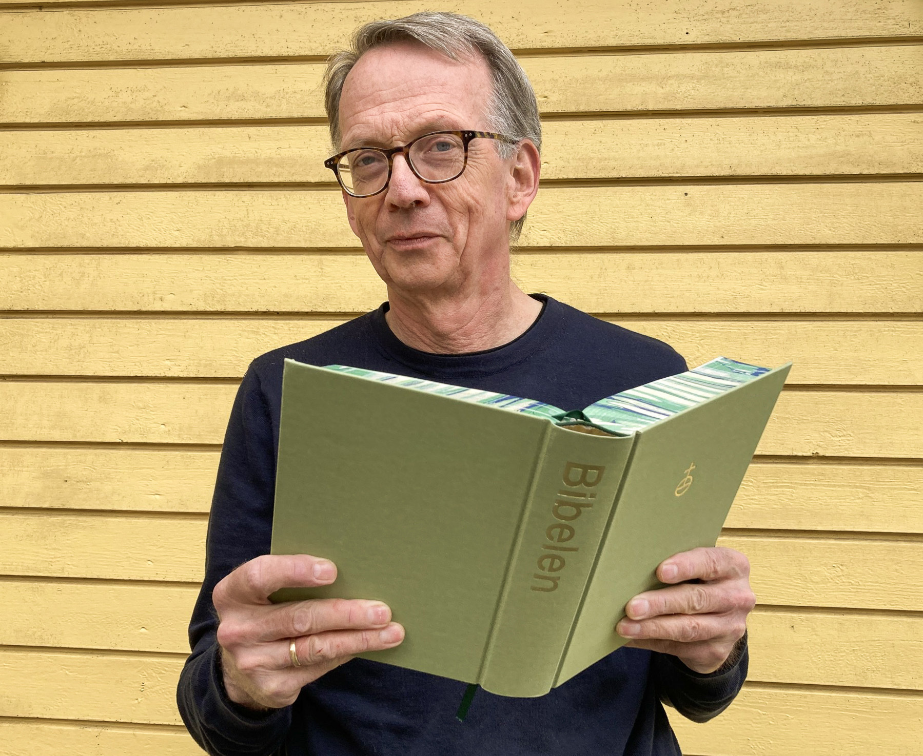 Mann holder en åpen bibel.