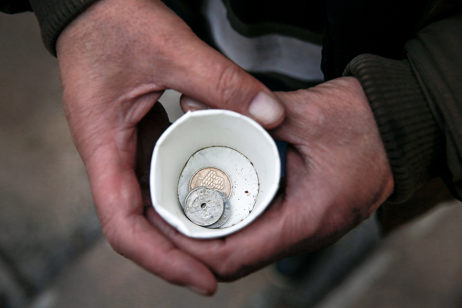 Bilde tatt ovenfra og ned i en pappkopp med litt penger i.