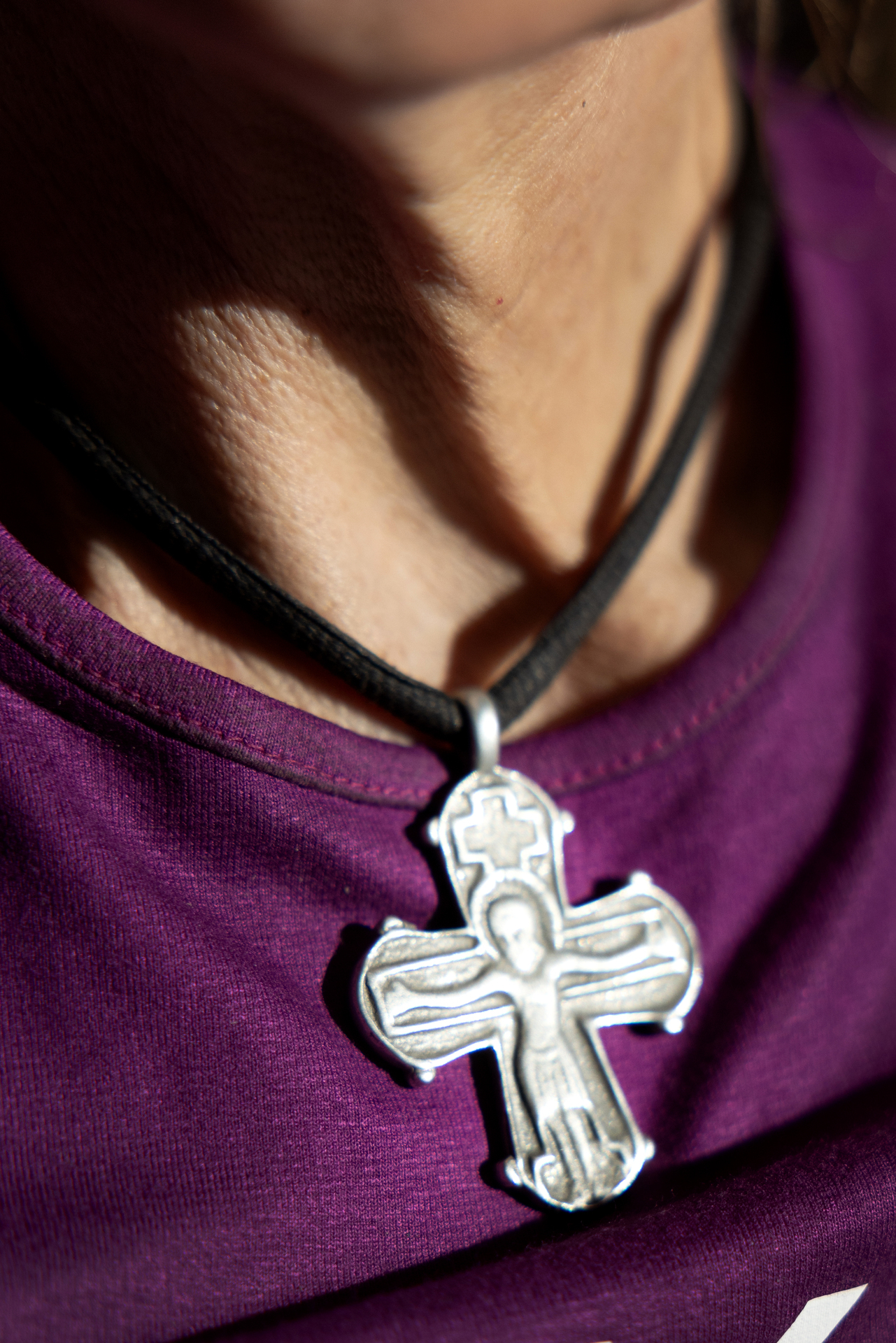 Foto: Nærbilde av halsgrop med et kors i sølvfarge med Jesus på. Han står med utstrakte armer.