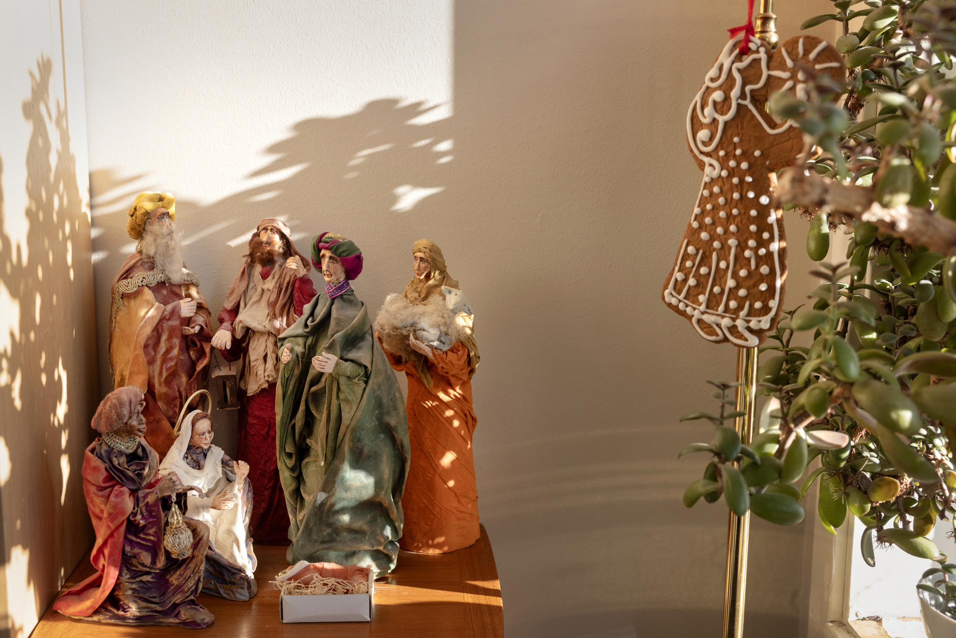 Foto: I en krok av rommet står en julekrybbe med tre konger, hyrder, Josef og Maria med Jesus-barnet. På en lampe like ved henger en pepperkakeengel.n pyntet