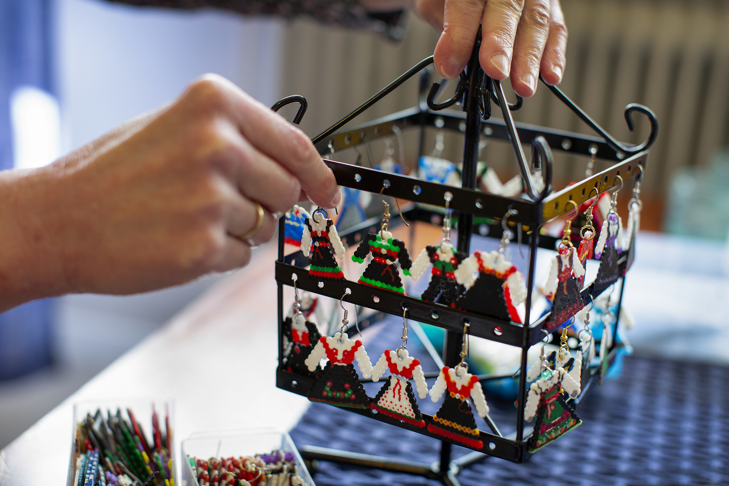 På et øredobbstativ henger rundt 30 små bunadsøredobber, av bunader fra forskjellige steder i landet. Perlene er så små at Viktoria bruker pinsett for å plassere hver enkelt av dem.