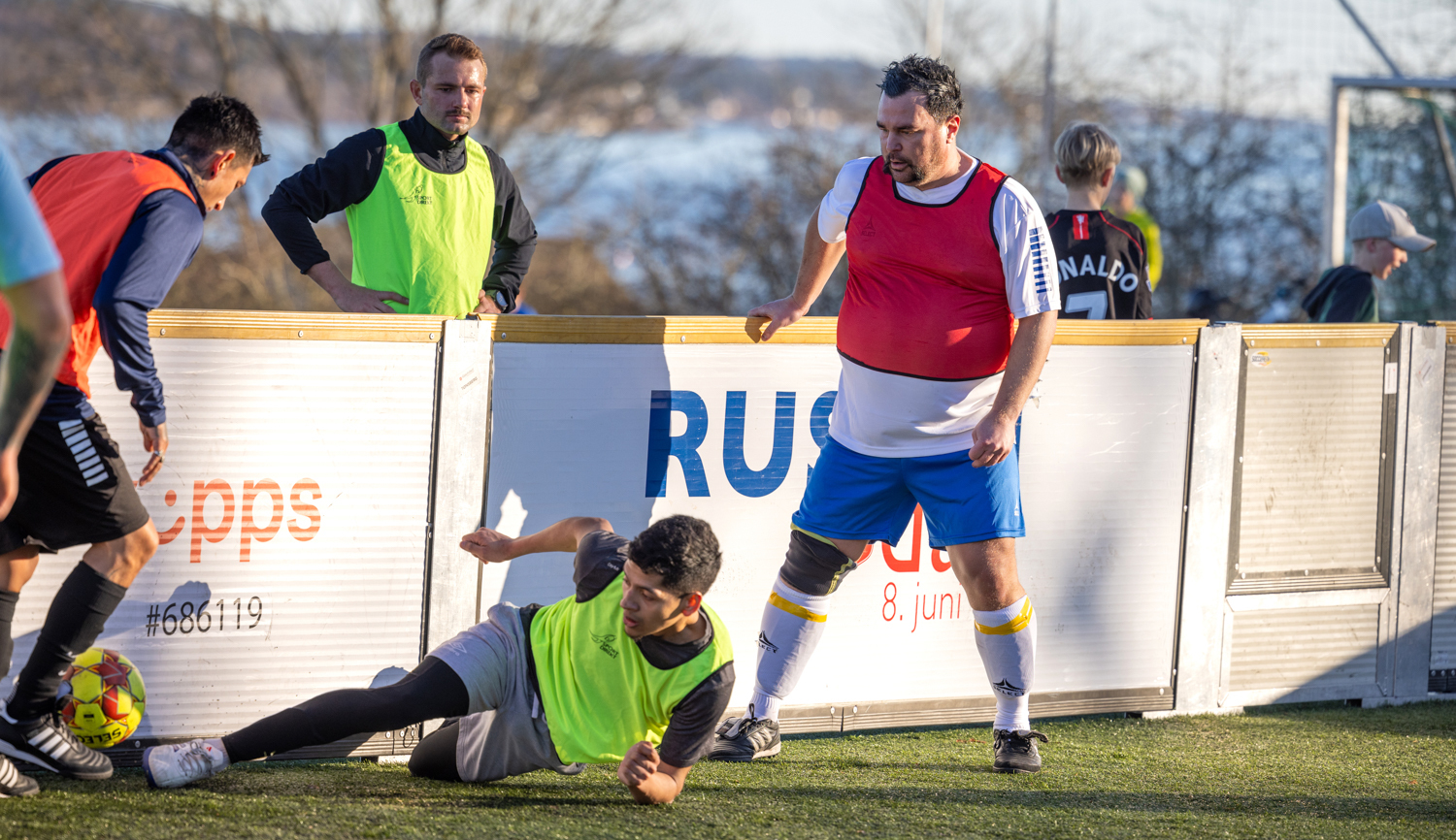 Foto: Flere menn som står utenfor eller spiller inni en ballbinge.