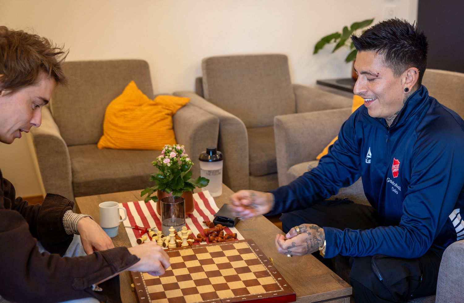 Foto: To menn spiller sjakk på et sofabord i en stue.