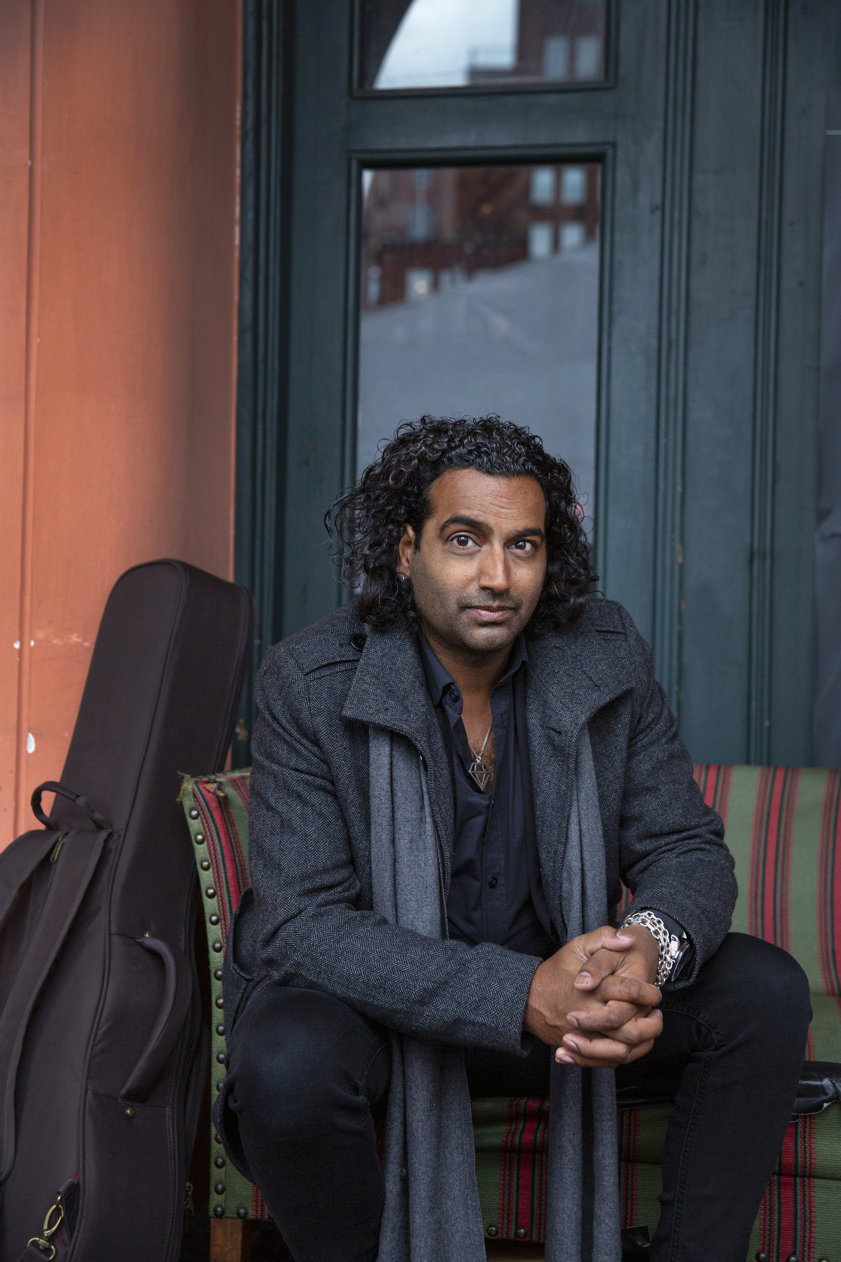 Cahnd sitter i en stripete sofa med gitaren ved siden av