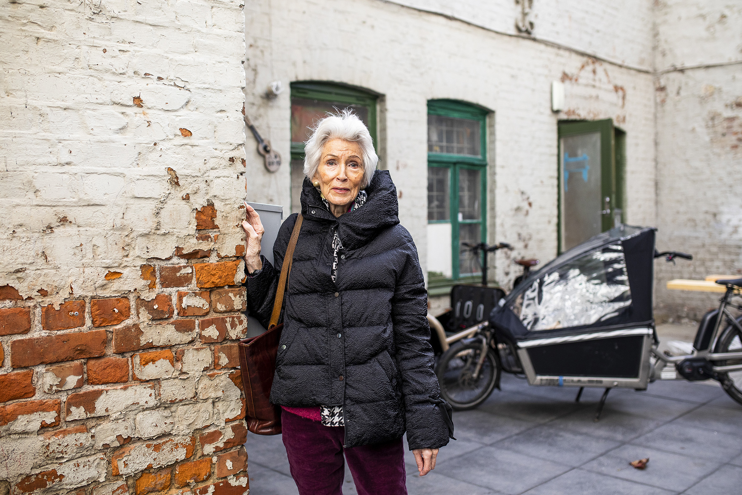 Charlotte lener seg inntil en hvit gammel murvegg.