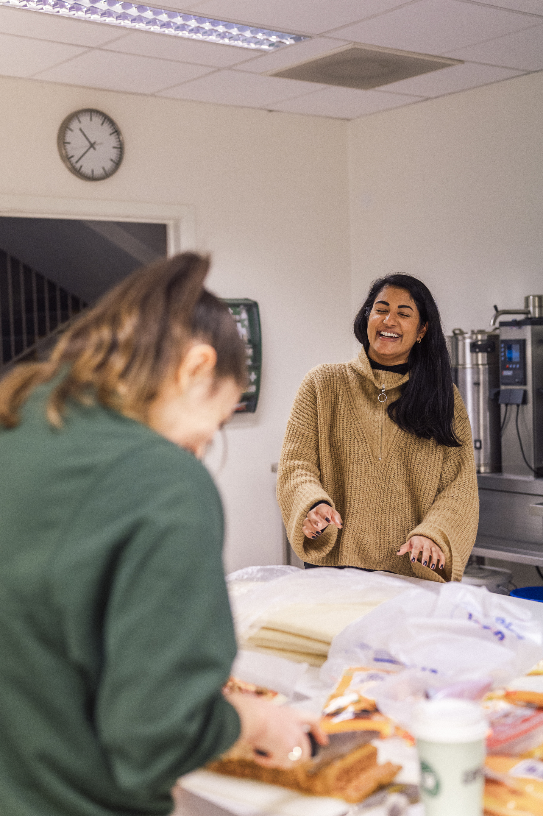Tine står leende på kjøkkenet sammen med en av ungdommene hun jobber med