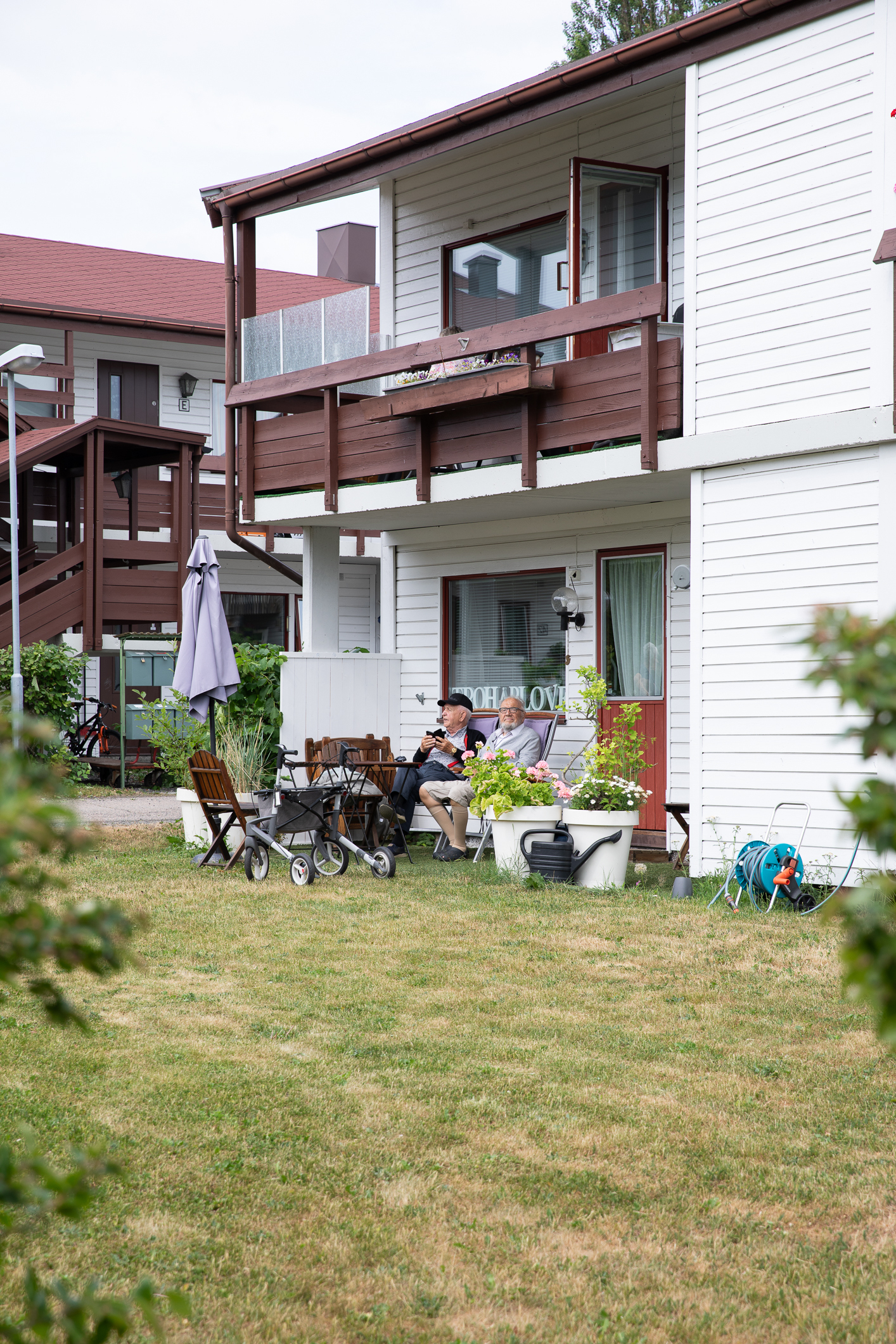 Bilde av to leilighetshus i to etasjer like ved hverandre. I forgrunnen sees gressplen og noen busker.