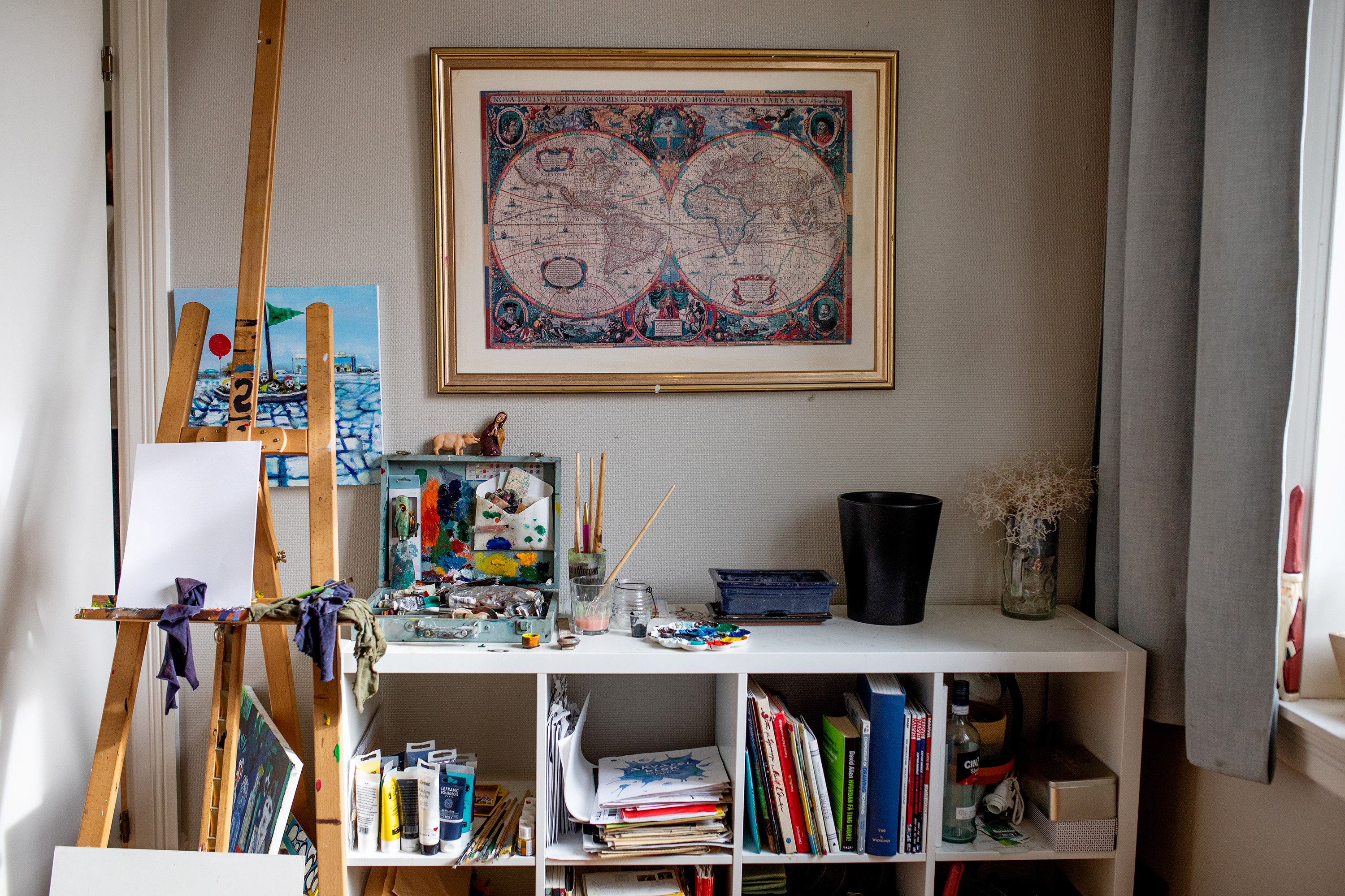 I leiligheten til Tom er det pent og ryddig, staffeli og malesaker er sirlig plassert i en bokhylle og stuen er full av grønne planter