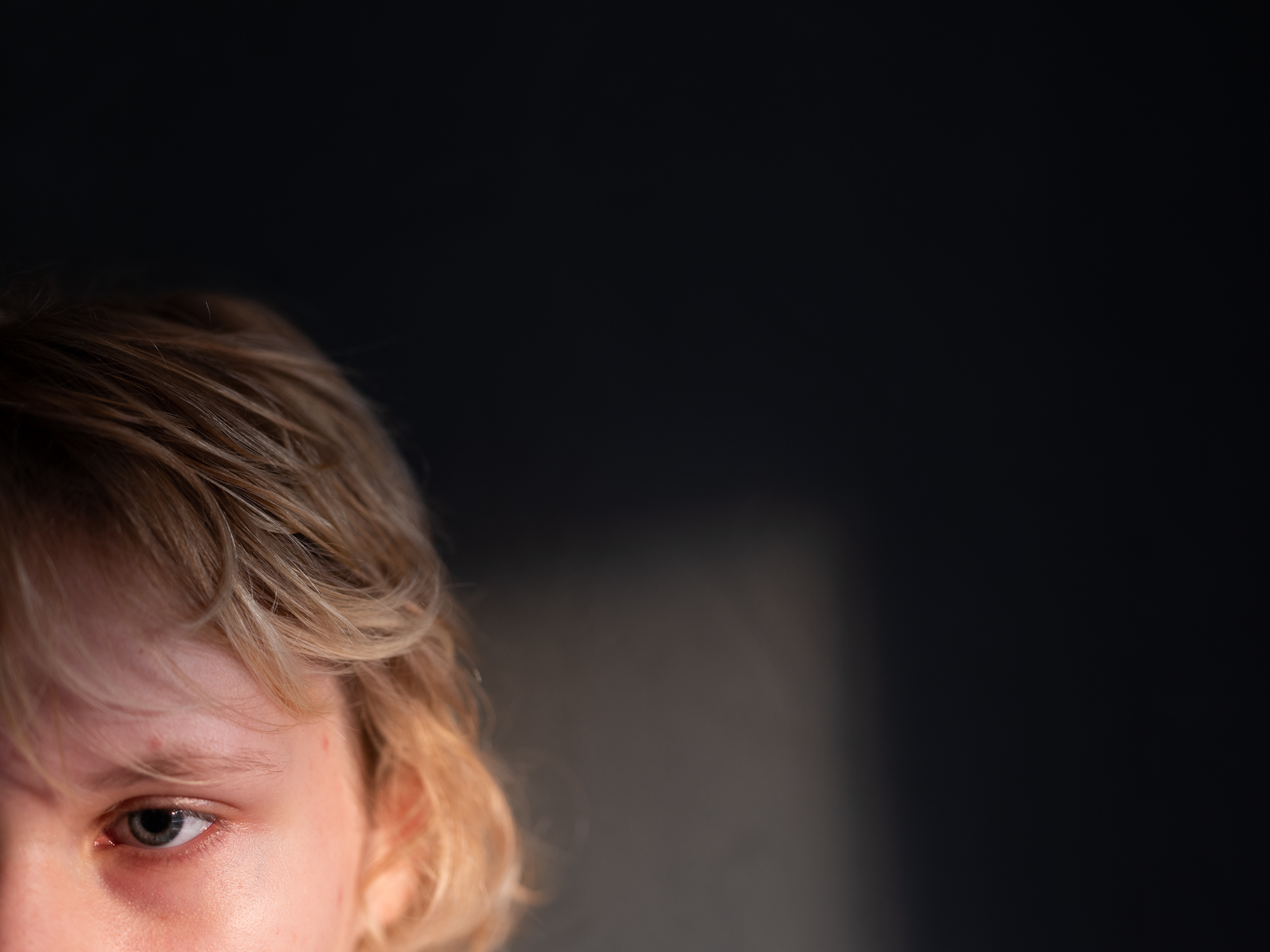 Utsnitt av et ansikt der vi ser et trist øye og lyst hår