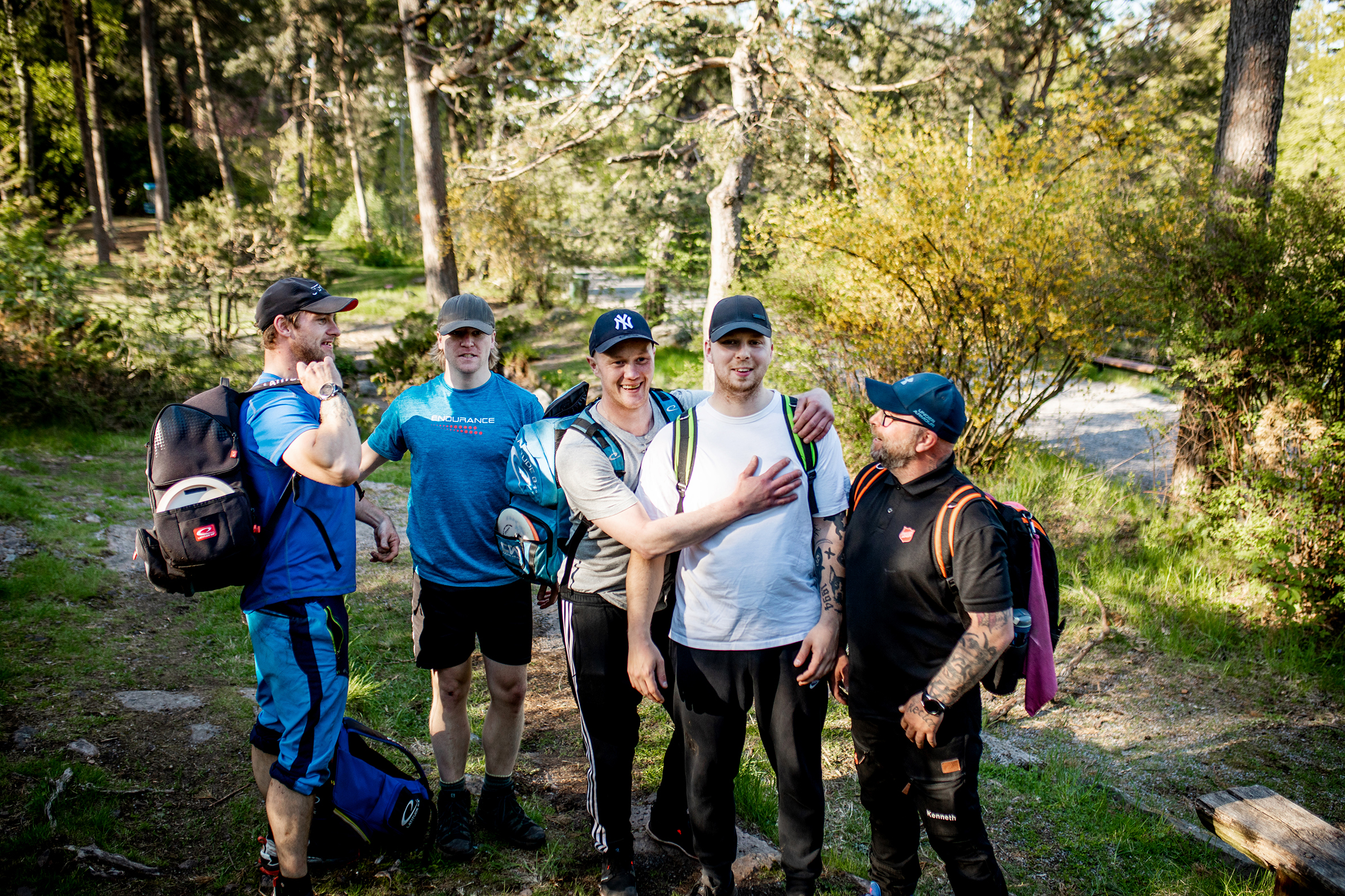 Gutta som spiller discgolf sammen er ute på banen som ligger inne i skogen
