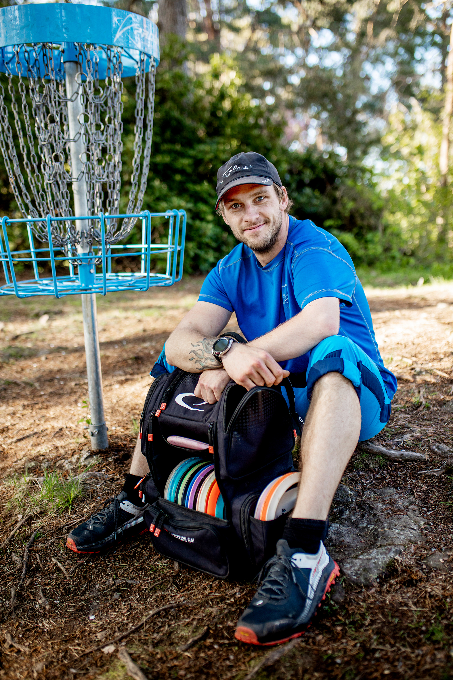 Simen er en av spillerene, her sitter han ved et av netene med bagen med discer mellom bena