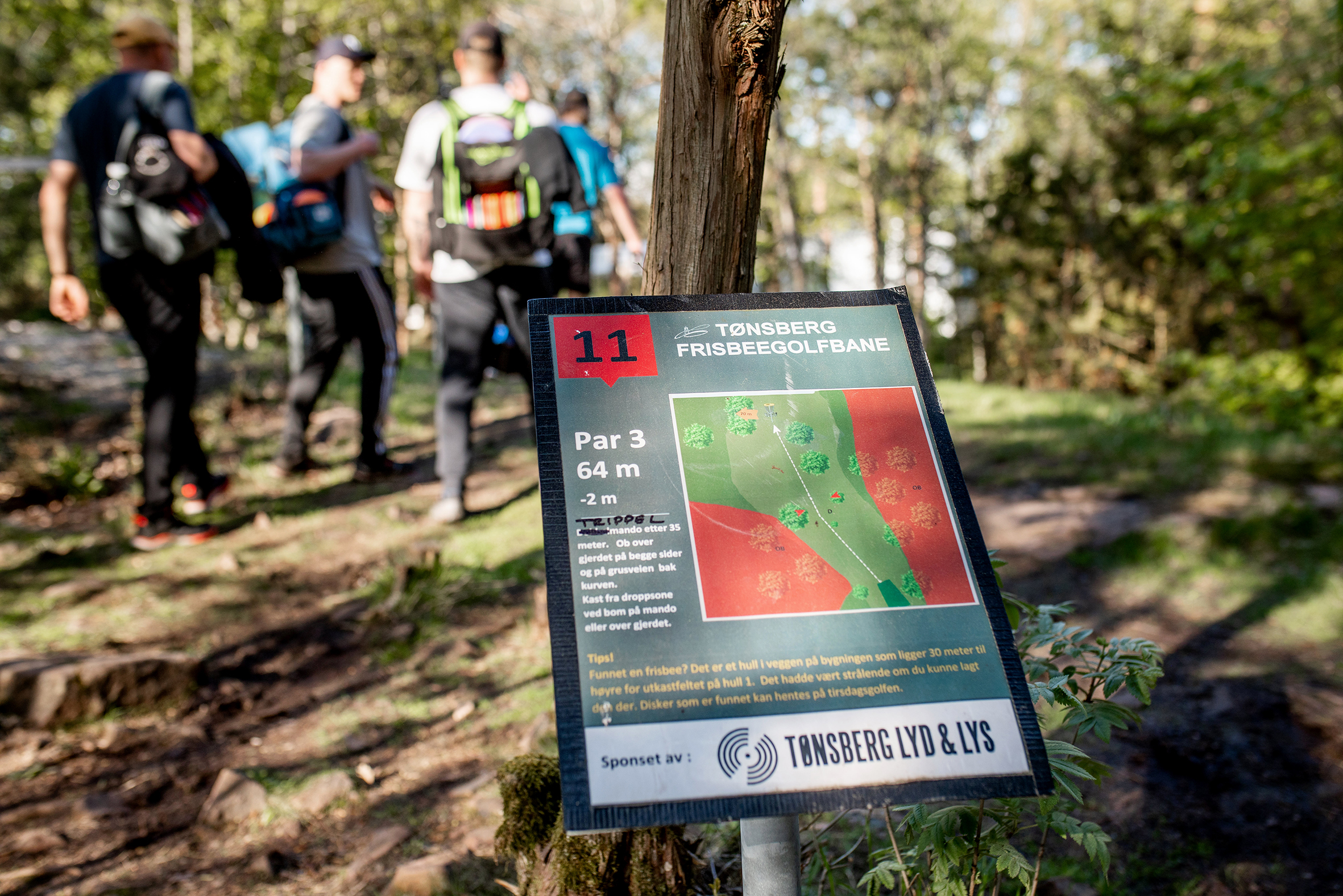 Gutta som spiller discgolf sammen er ute på banen som ligger inne i skogen