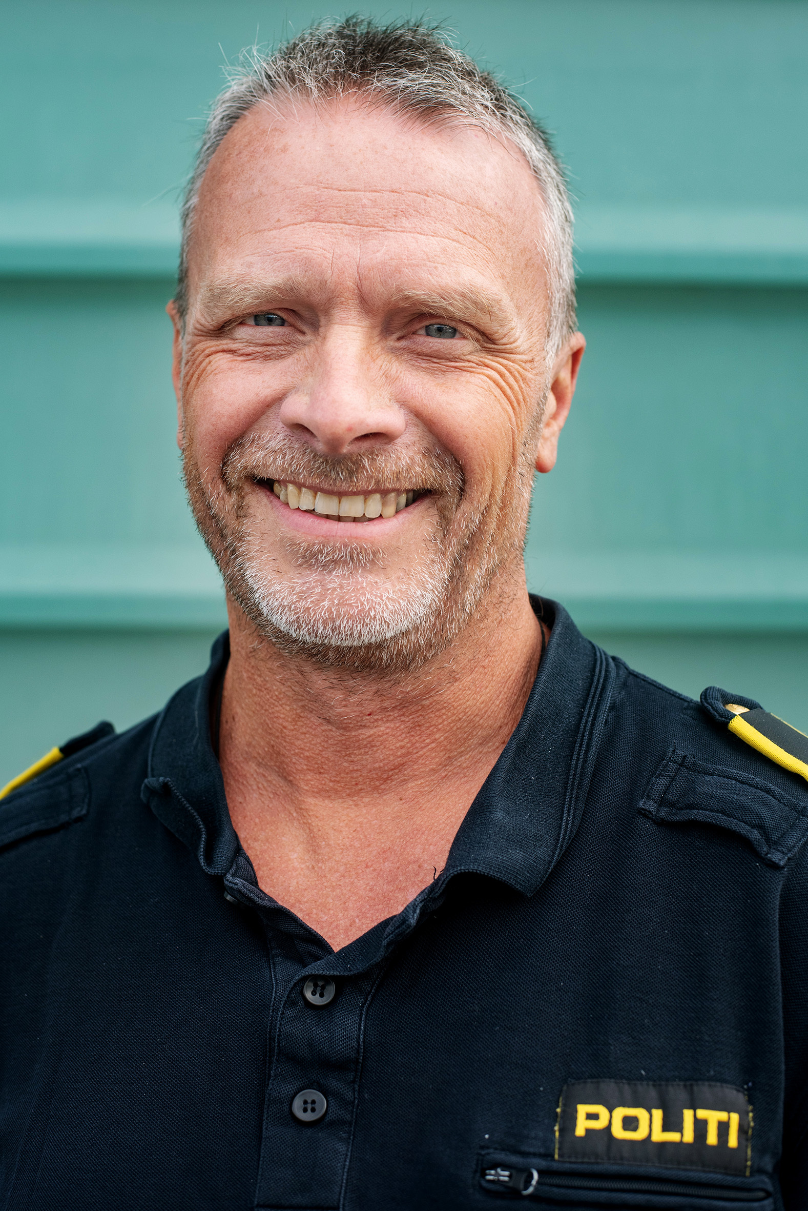 Ebbe Kimo i politiuniform står inntil en grønn murvegg