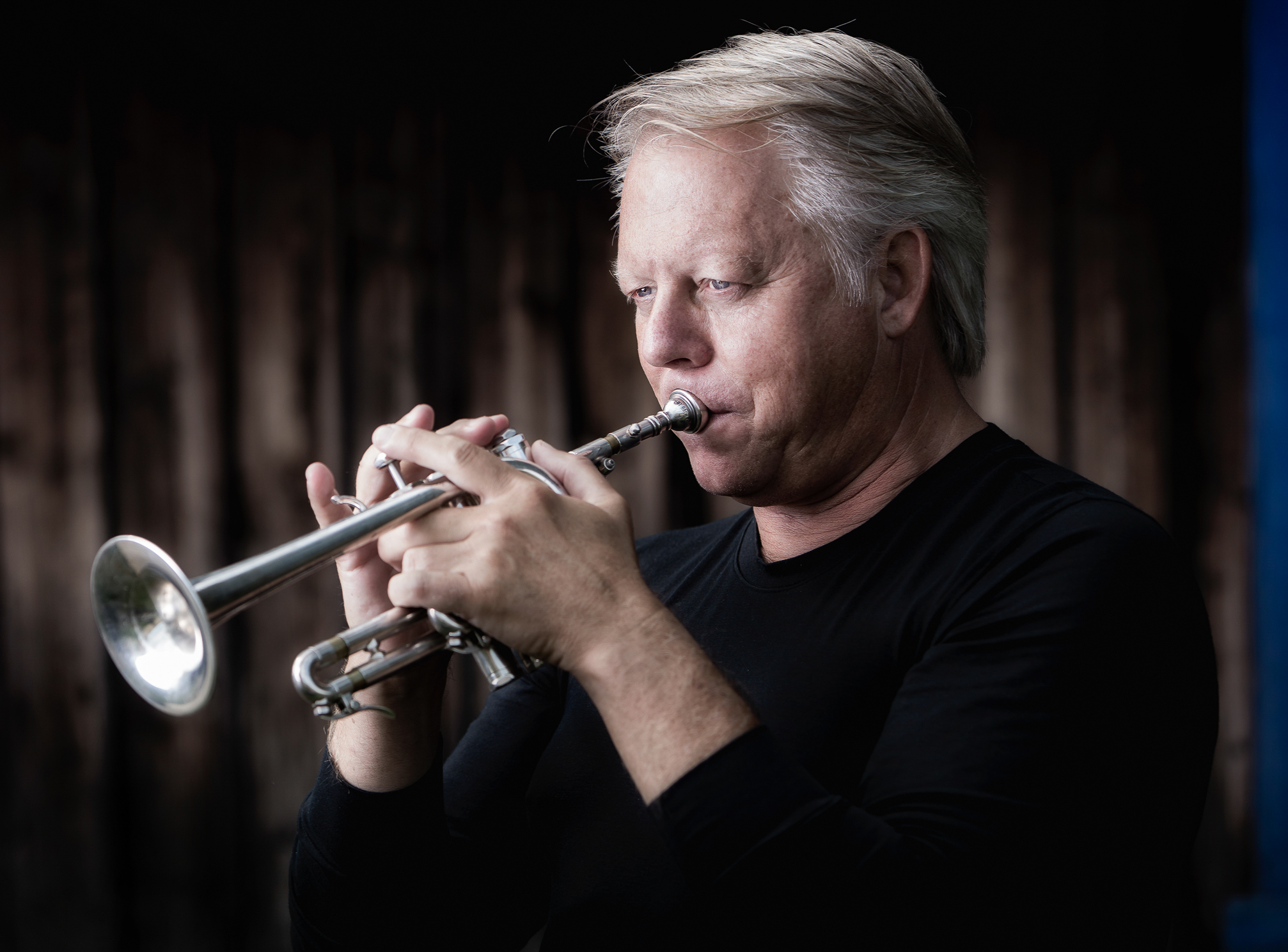Nærbilde av en godt voksen mann som spiller trompet. Han ser nedover sitt instrument.