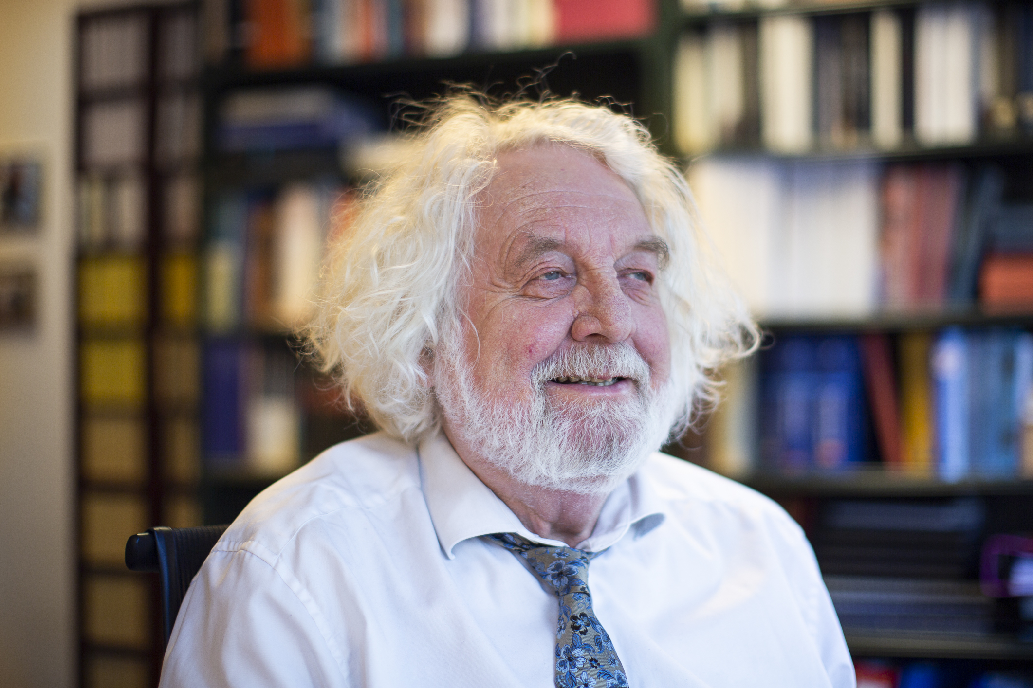 Edvard smiler til fornøyd til siden på kontoret sitt i en hvit skjorte.