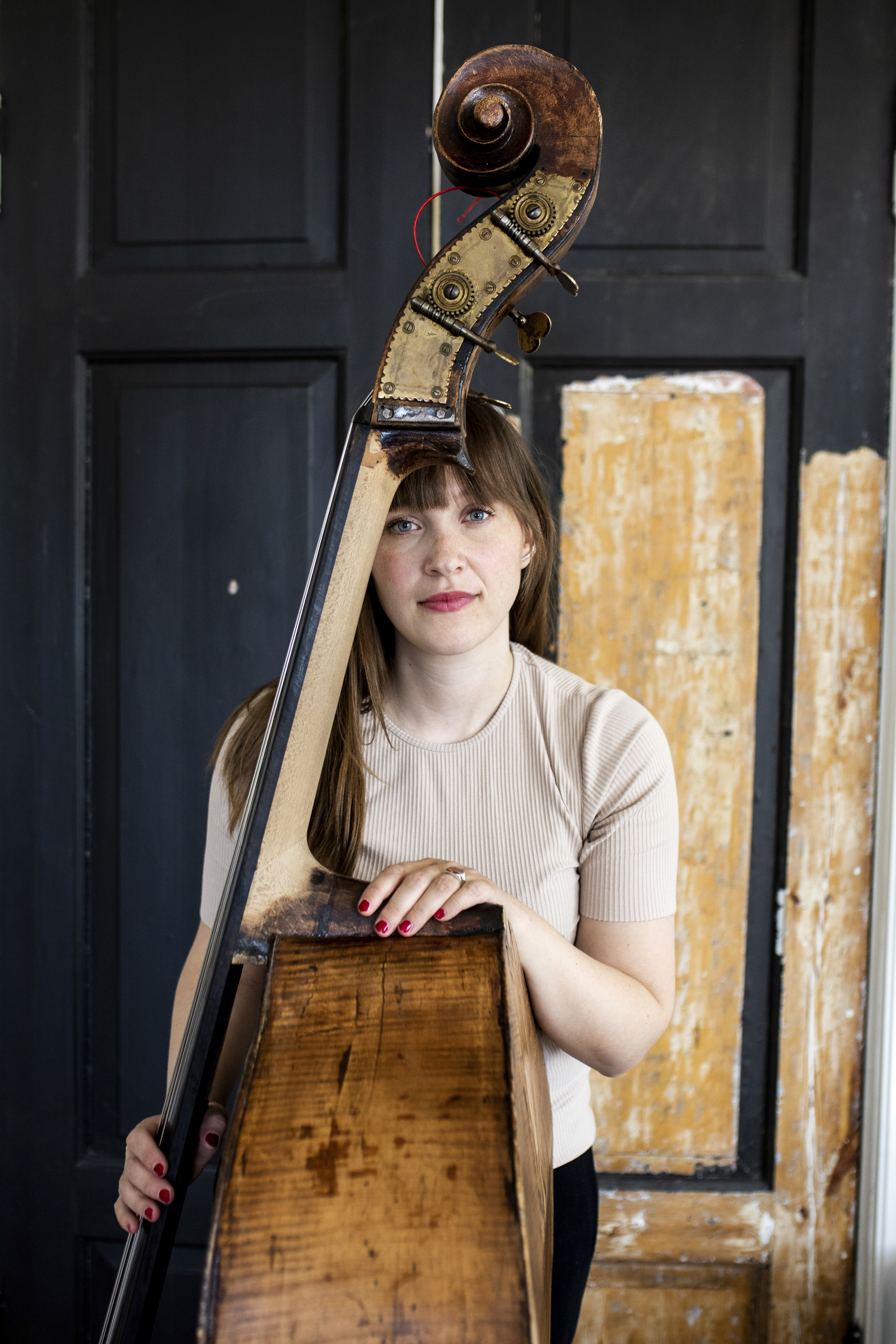 Ellen Andrea Wang poserer sammen med kontrabassen sin foran en gammel, slitt tredør.