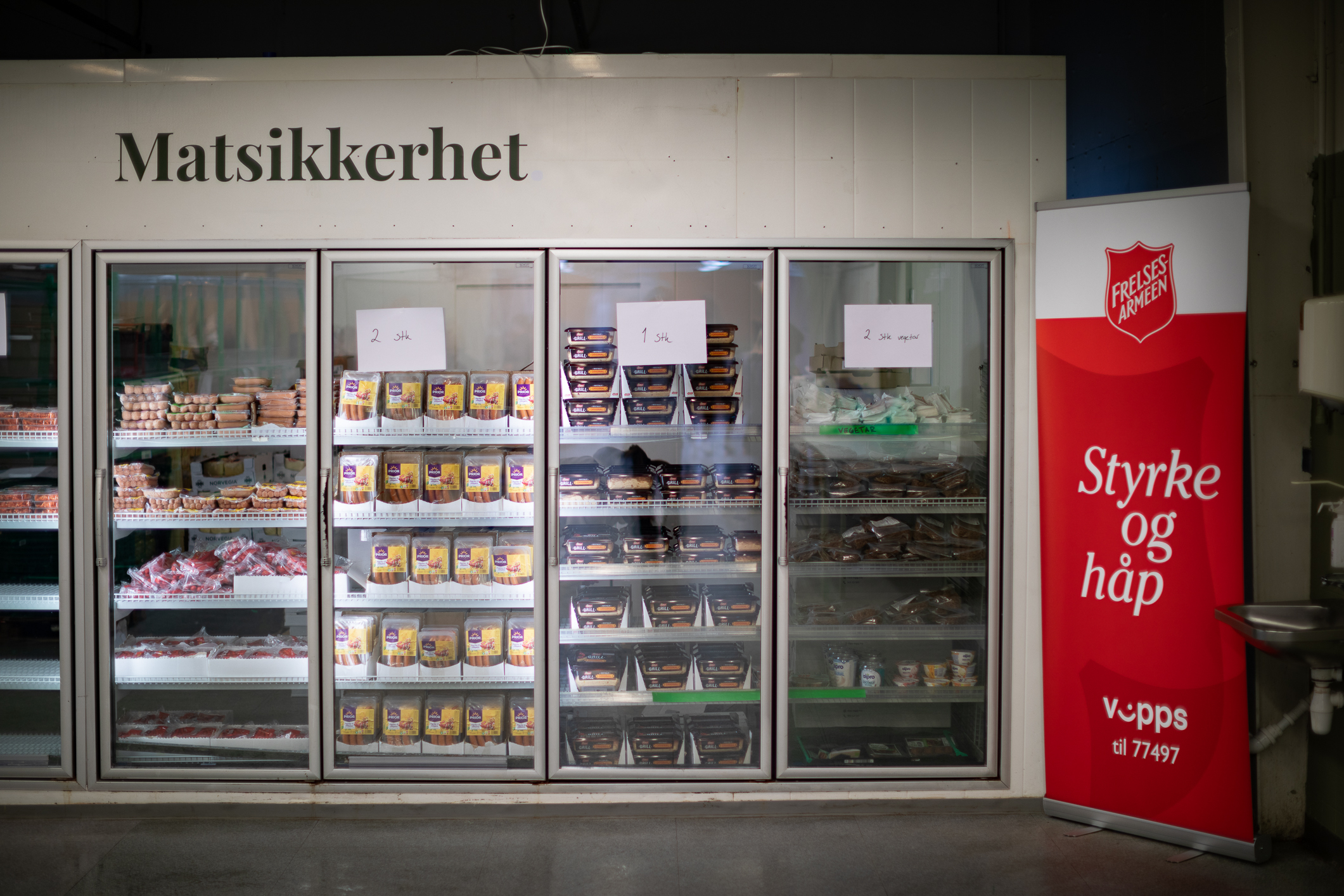 Bilde av kjøleskapsdørene med mat på kjølerom. På veggen står det matsikkerhet.