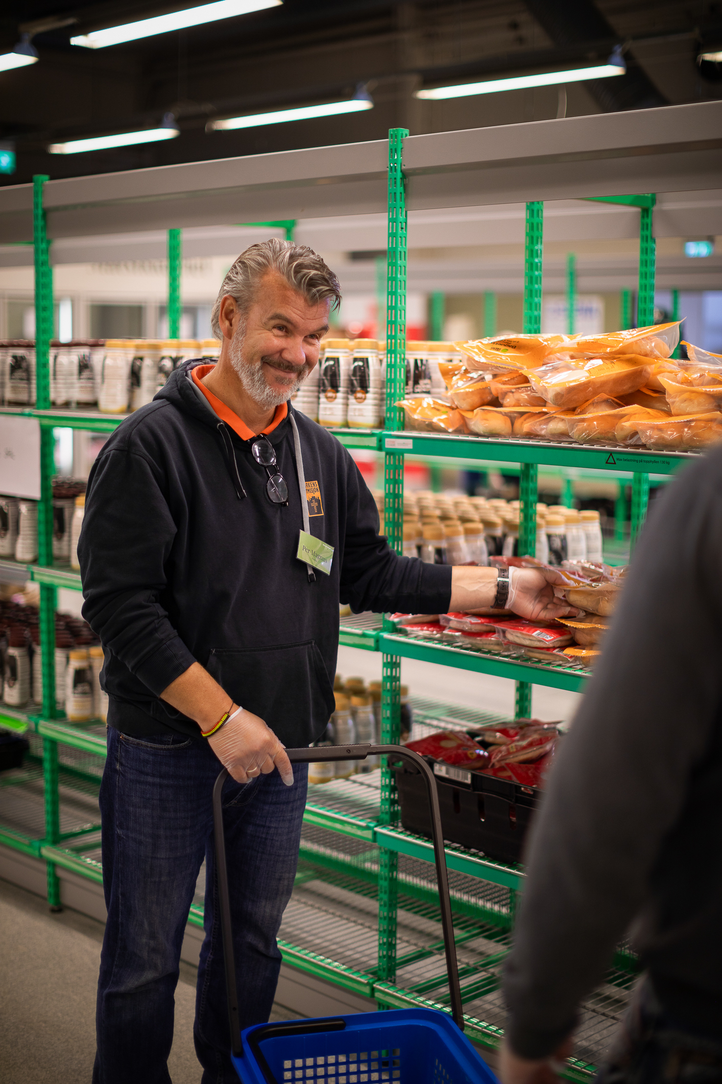 Per Magnus Lindberg fra Kirkens Bymisjon deler ut mat ved en av butikkhyllene.