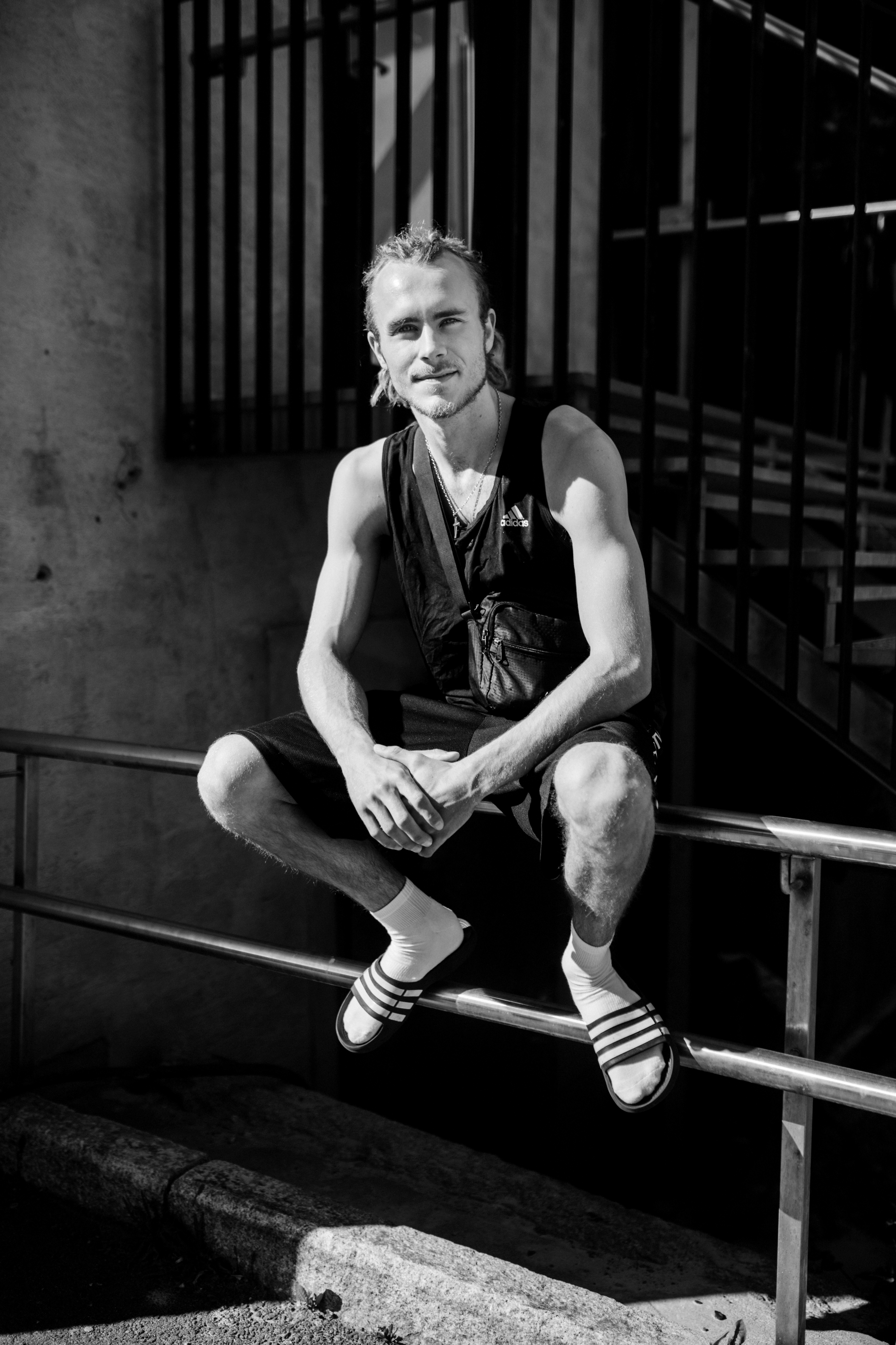 Bildet er i svart-hvitt og viser Endre Grytting som sitter på et gjerde og smiler, iført mørk singlet og shorts.