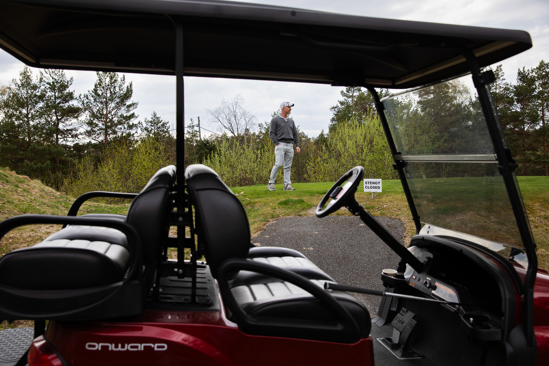 Foto: To bilder der det første viser en mann som peker opp på en tavle på et kontor der det står "Hole in One". Det andre bildet viser ham på banen, sett gjennom den luftige golfbilen.