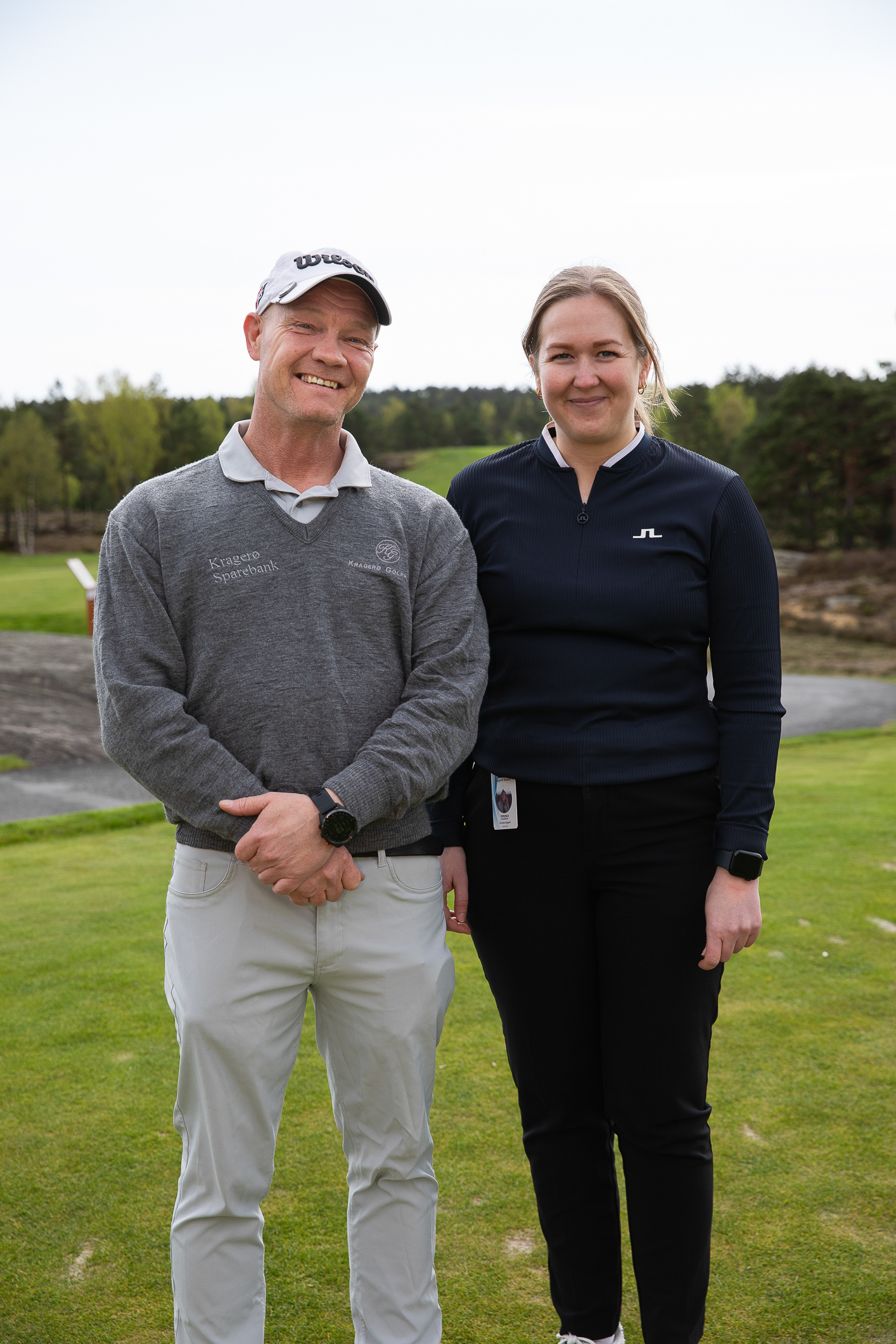 Foto: Mann og kvinne står ved siden av hverandre med golfbane i bakgrunnen.
