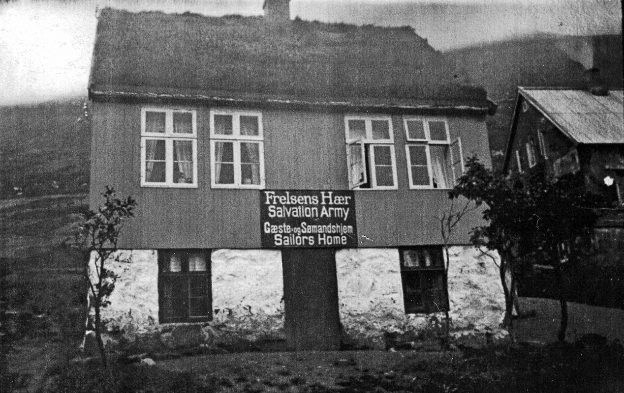 Foto: Svart-hvitt-bilde av kjempegammelt hus med skilt utenfor der det står: "Frelsens Hær – Salvation Army / Gæste og Sømandshjem – Sailors Home".