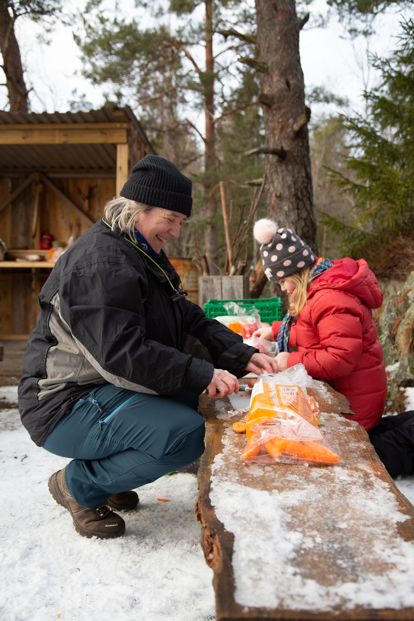 Bente Eriksen, speiderleder, lager mat sammen med et av barna foran bålet.