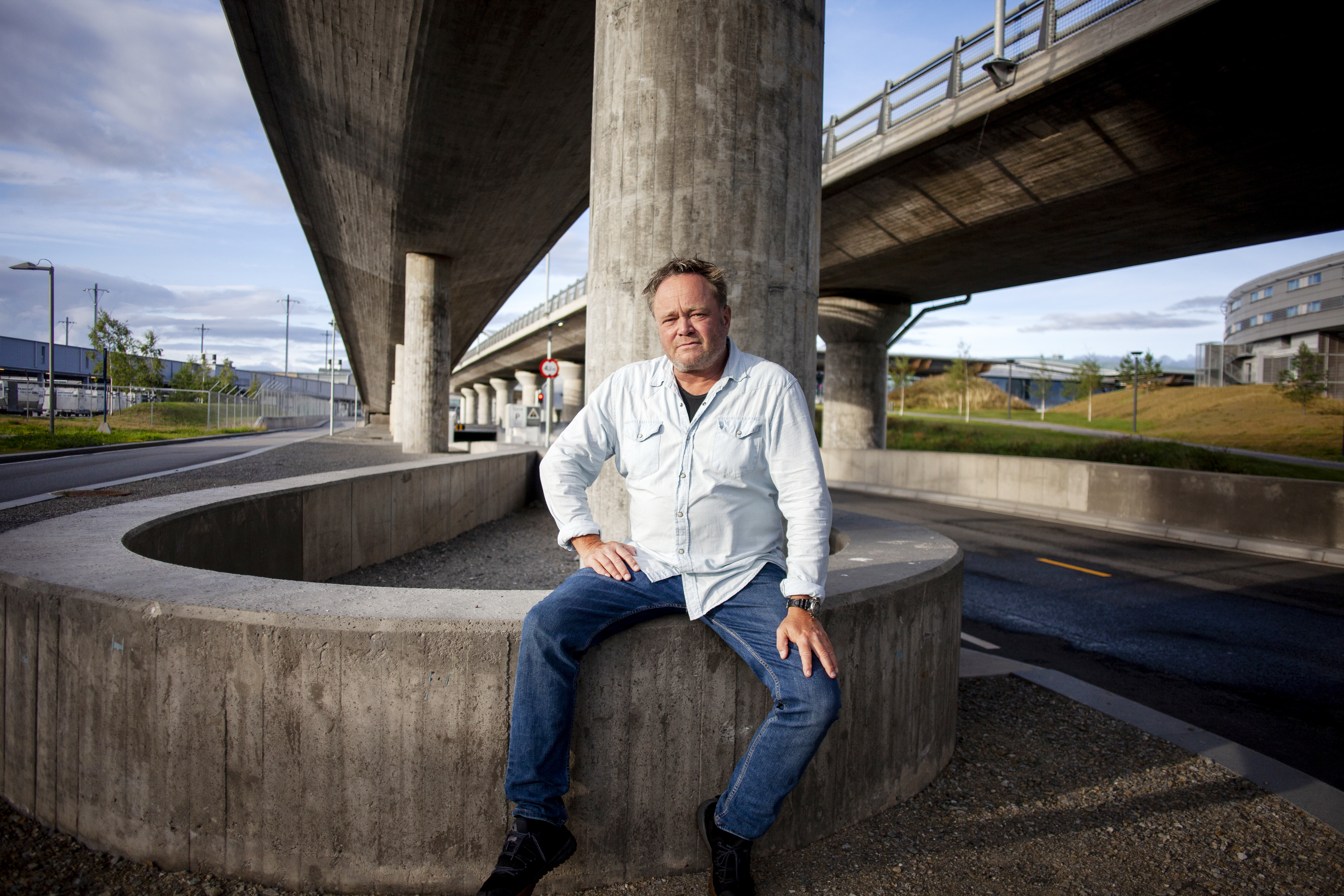 Fredrik Græsvik sitter på et betonggjerde ved Gardermoen lufthavn
