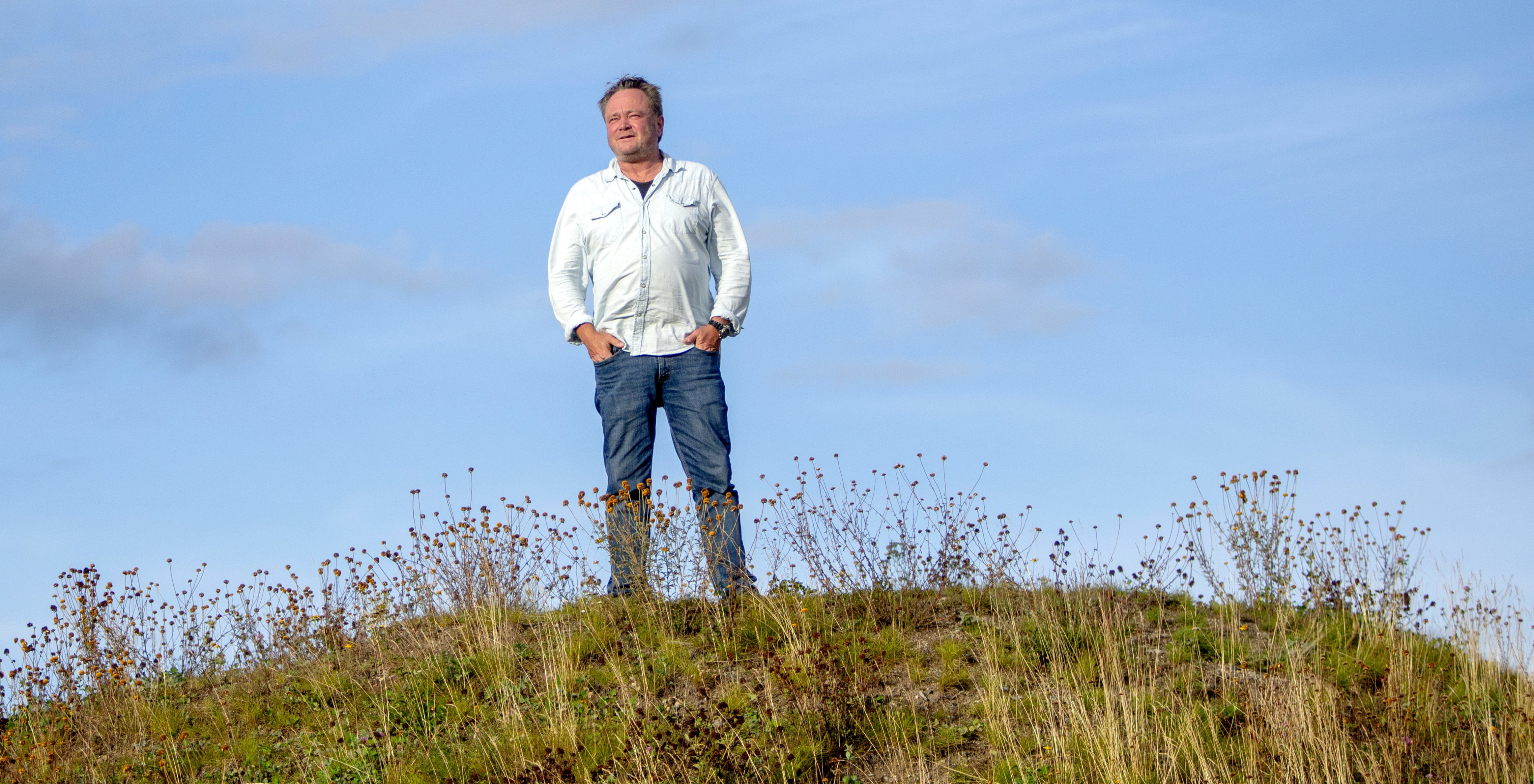 Fredrik Græsvik står på en høyde og skuer utover utsikten.