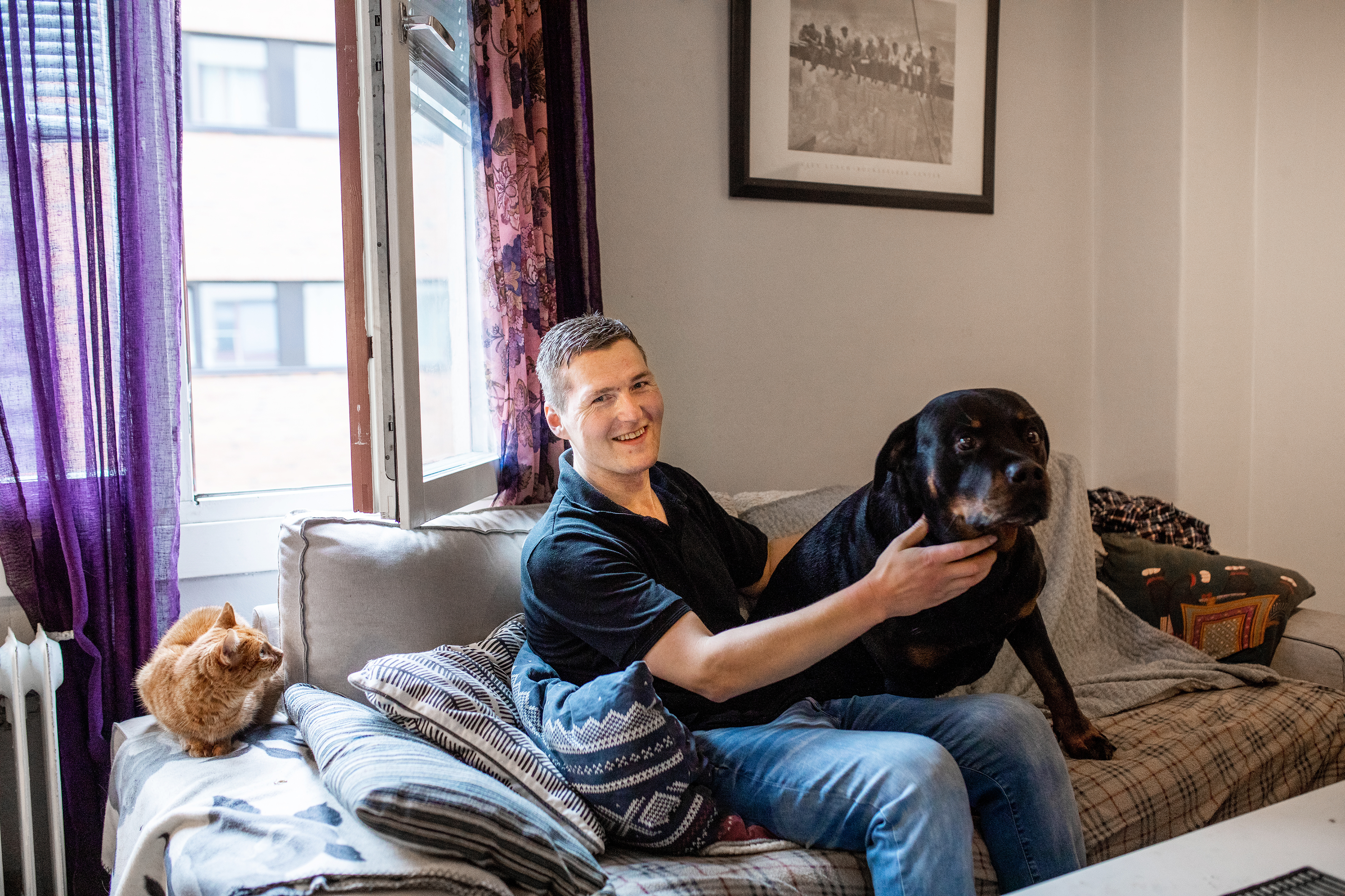 Alexander sitter i sofaen, i sin lelighet, sammen med l rottweileren Compis og katten Frida.