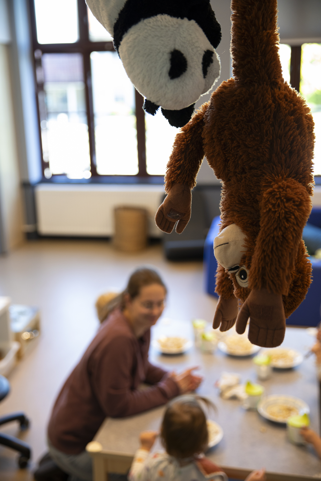 Foto: I en av barnehagens seks småbarnsavdelinger, sitter fem ettåringer rundt et lite bord med hver sin grøtbolle. Ned fra taket henger det noen kosedyr.