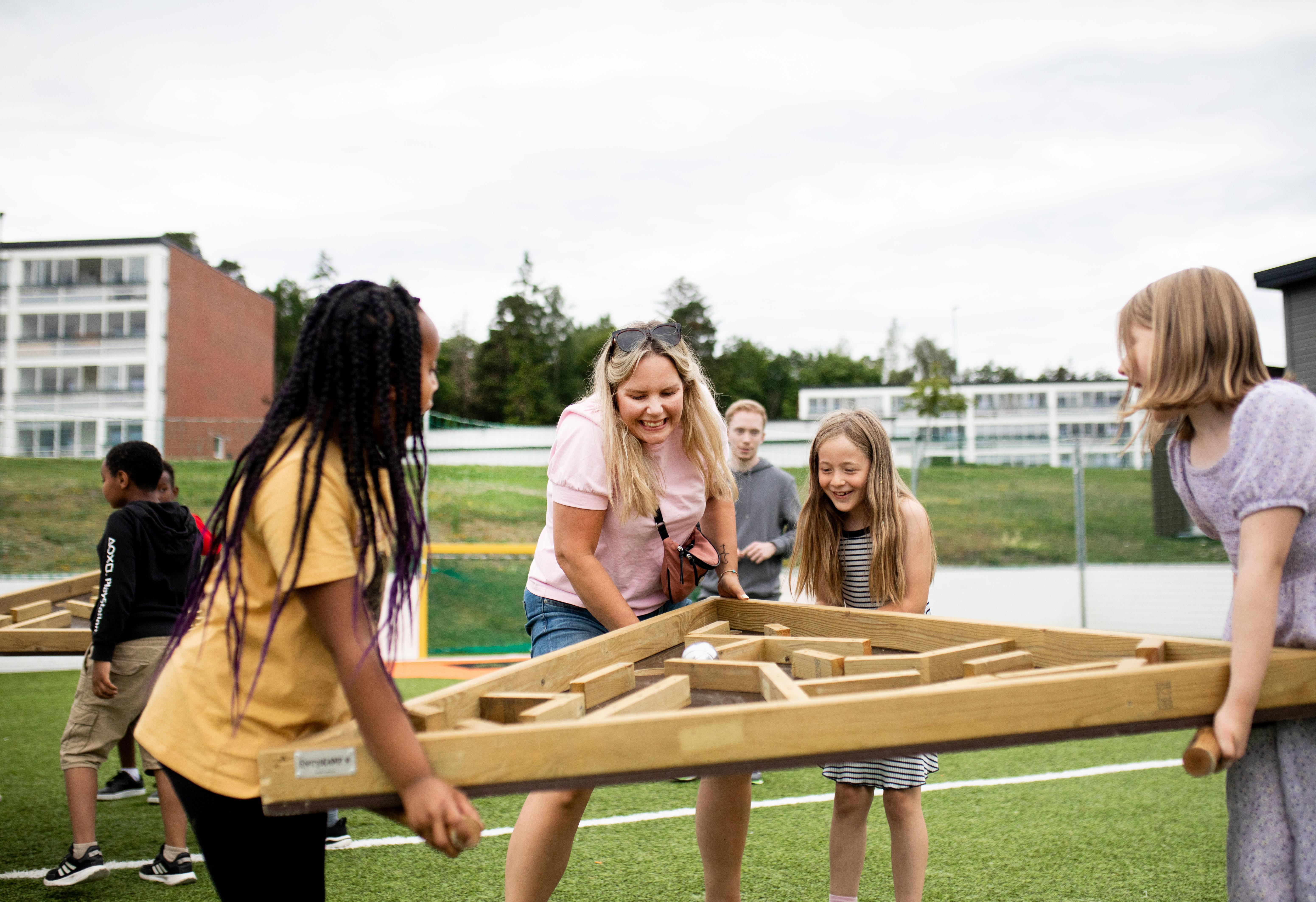 Tre unge ledere sitter på et bord foran FA kurssenter på Jeløy. De hjelper til med lek og moro for barna.
