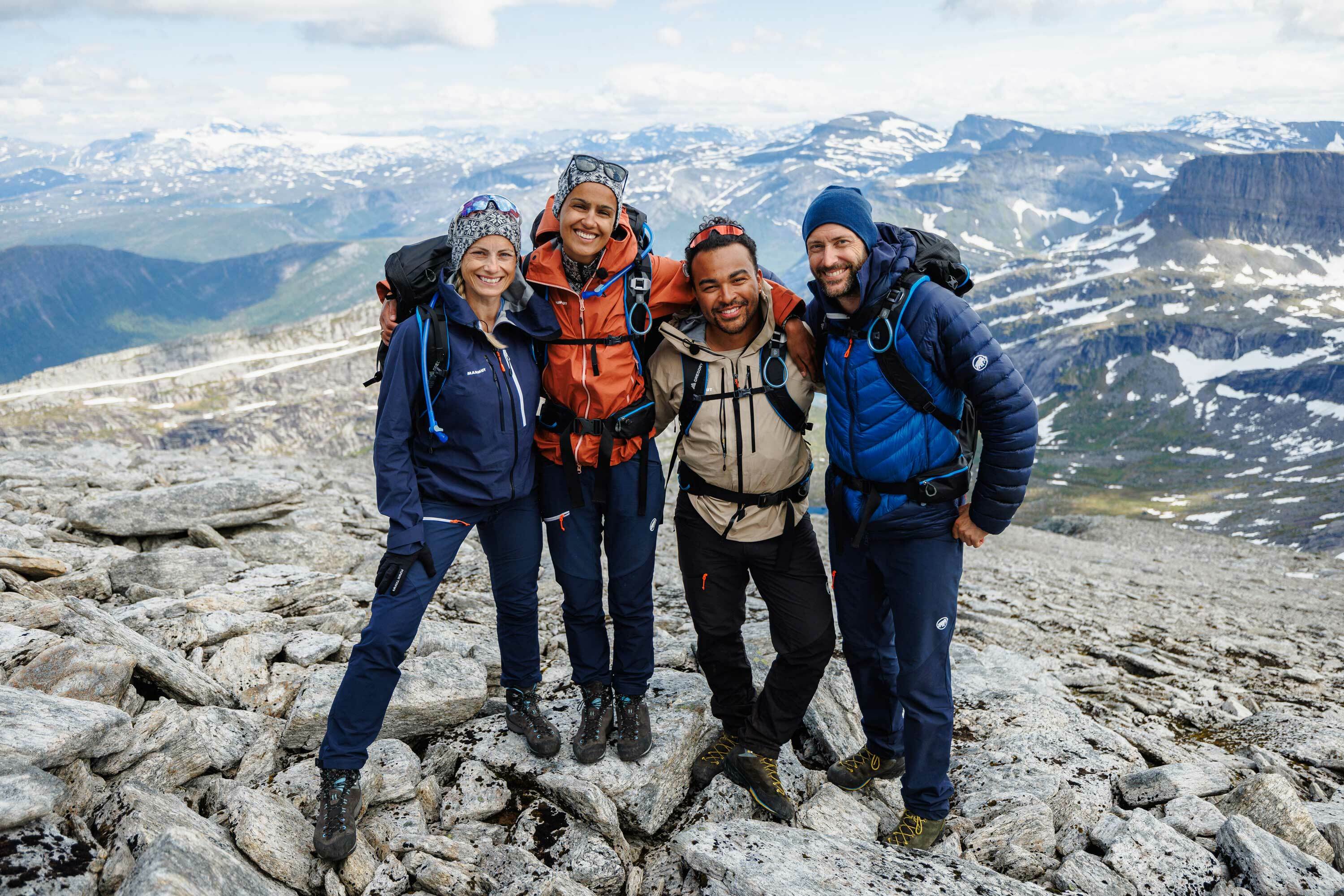 Fire fjellkledte deltakere på en fjelltopp.