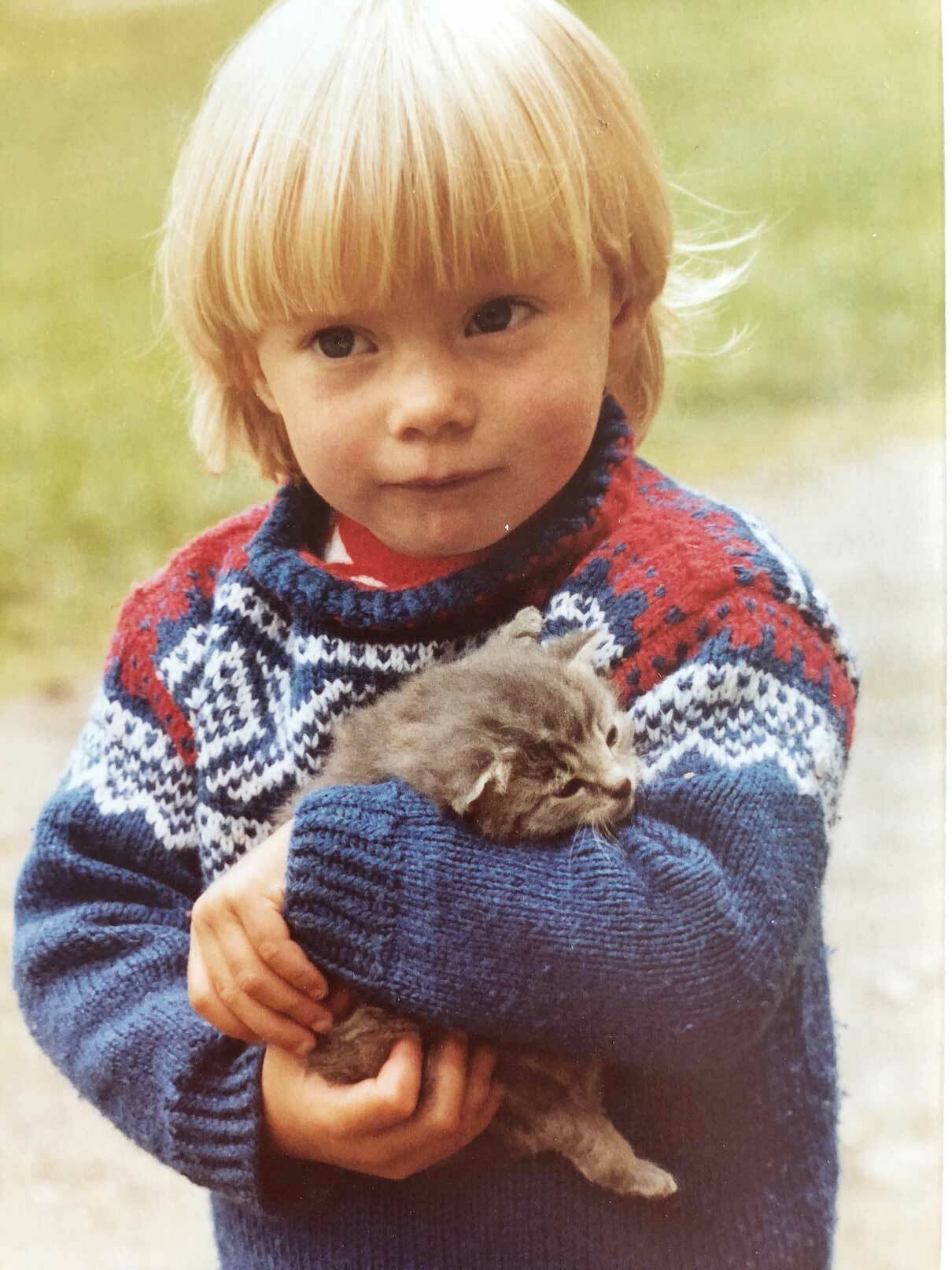 Eldre bilde av en liten lyslugget jente som holder en liten kattunge.