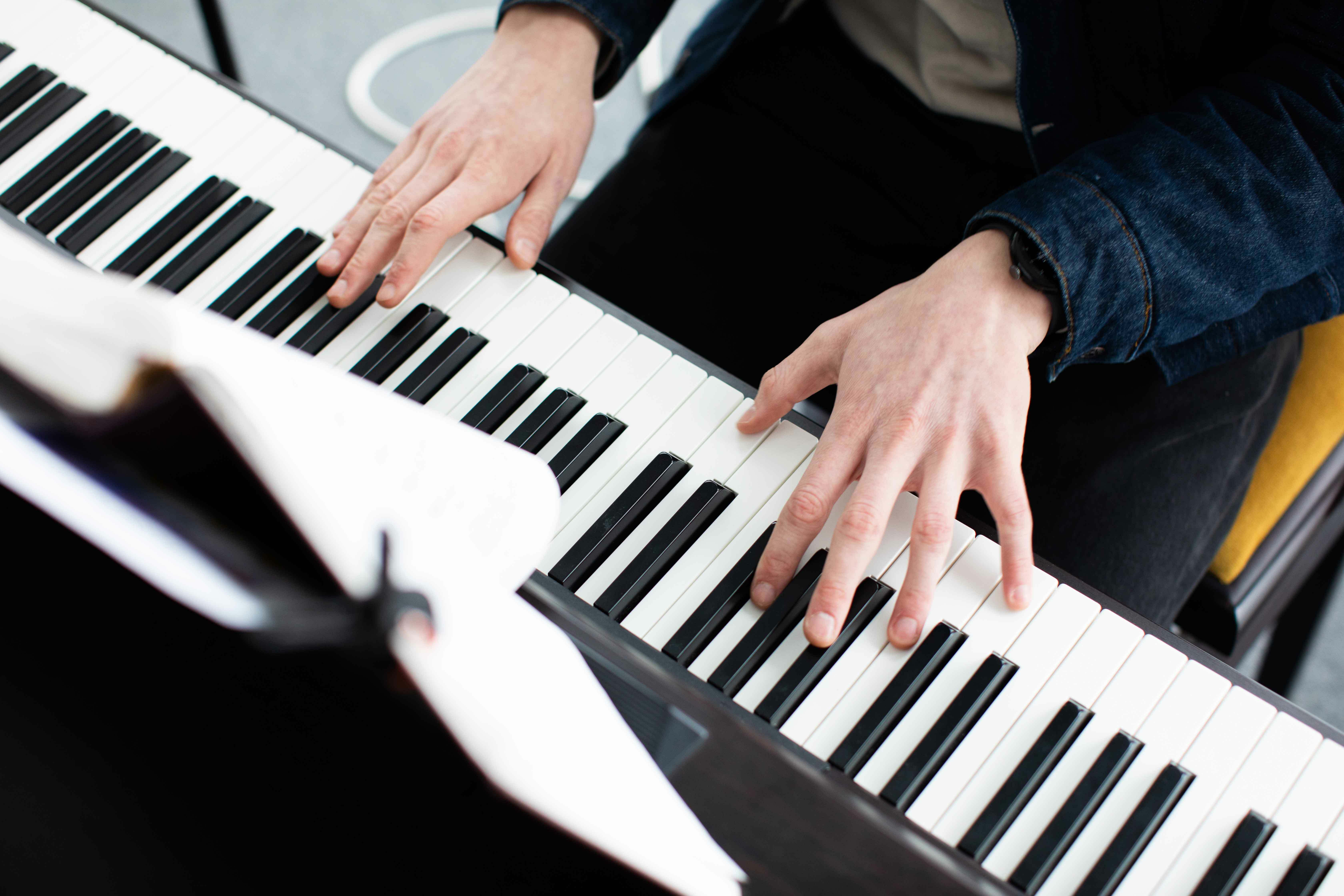 To hender som ligger over tangentene på et piano