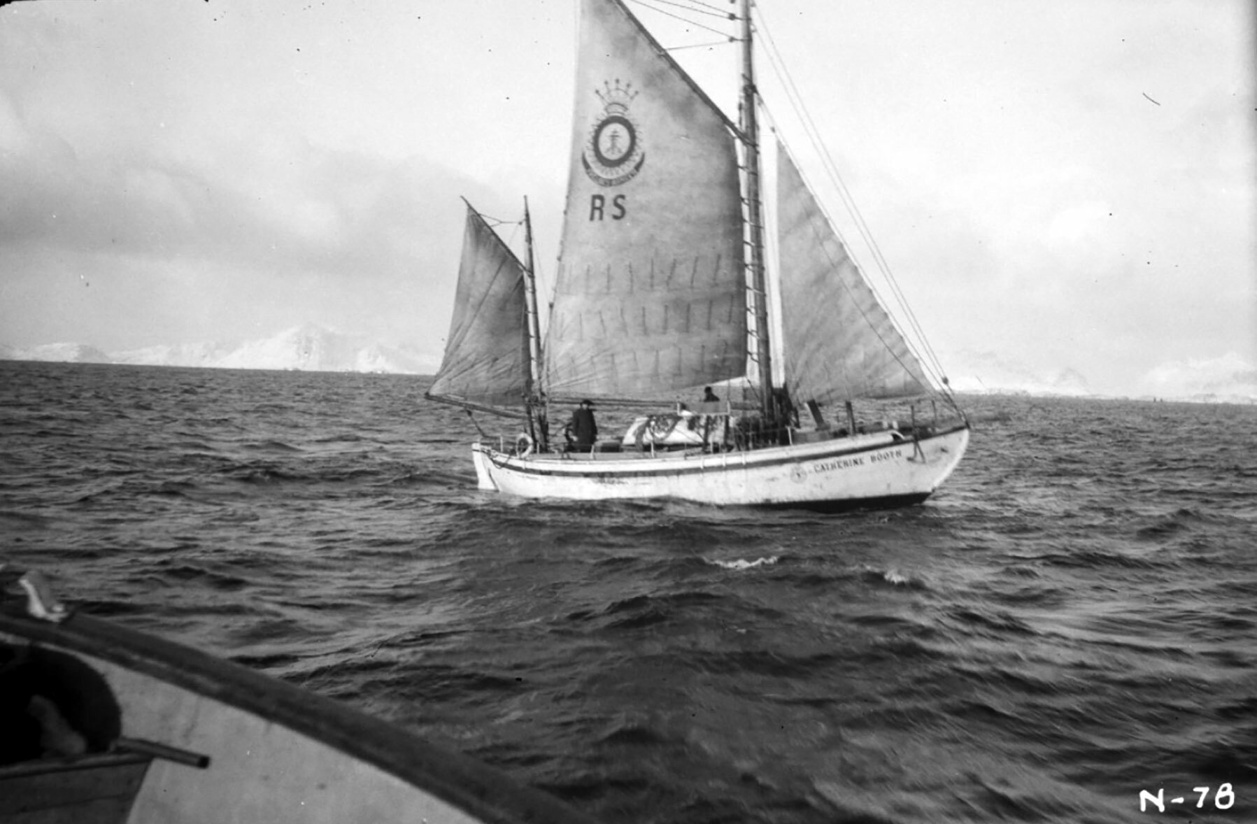 Foto: Gammelt sort-hvitt-bilde av en redningsskøyte ute på havet. Den har tre av sine seil oppe.