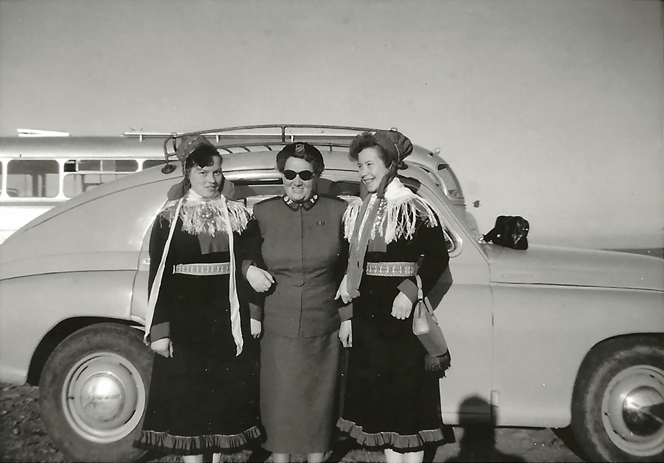 Foto: Gammelt svart-hvitt-bilde av en voksen kvinne i uniform fra Frelsesarmeens står arm i arm med to unge jenter i samisk folkedrakt.